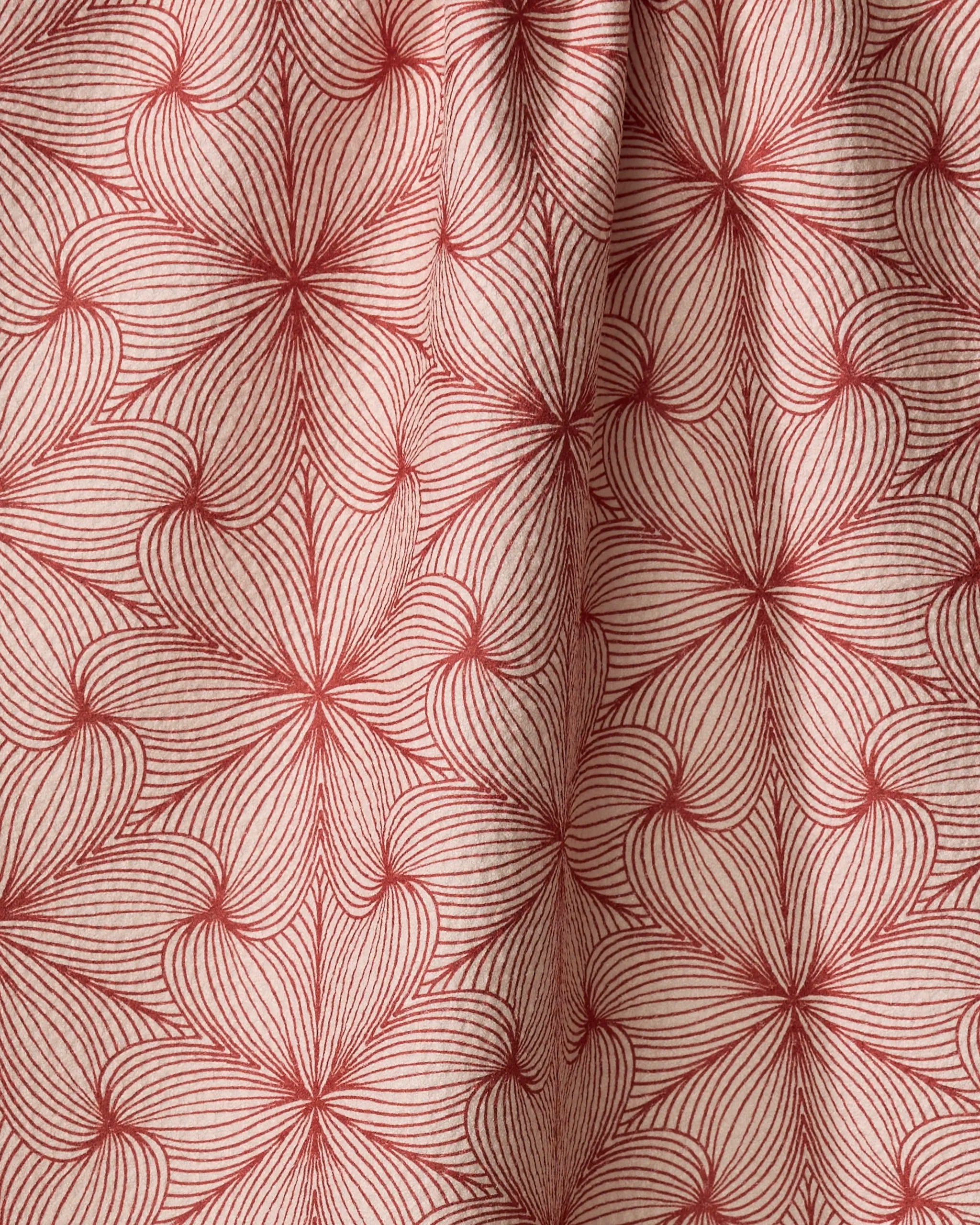 Red, thin, radiating lines form overlapping petal or leaf shapes on the cream-colored, textured "Lined" recycled kitchen towel by Marta Harvey. Gentle folds create shadows and depth in its geometric floral pattern.
