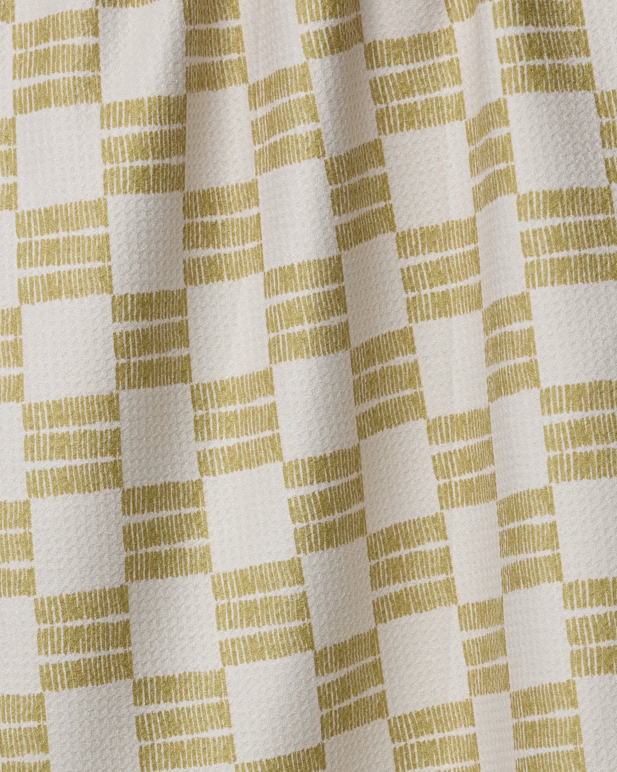 Close-up of the Anna Christian Linnea kitchen tea towel, featuring ultra-absorbent fabric with a checkered cream and light olive pattern. Olive squares display short horizontal lines. The textured towel appears slightly gathered.