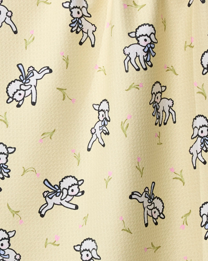 Little Lamb by Geometry features playful white lambs with blue bows among green plants and pink flowers on a textured light yellow background—ideal for a charming, recycled material tea towel.