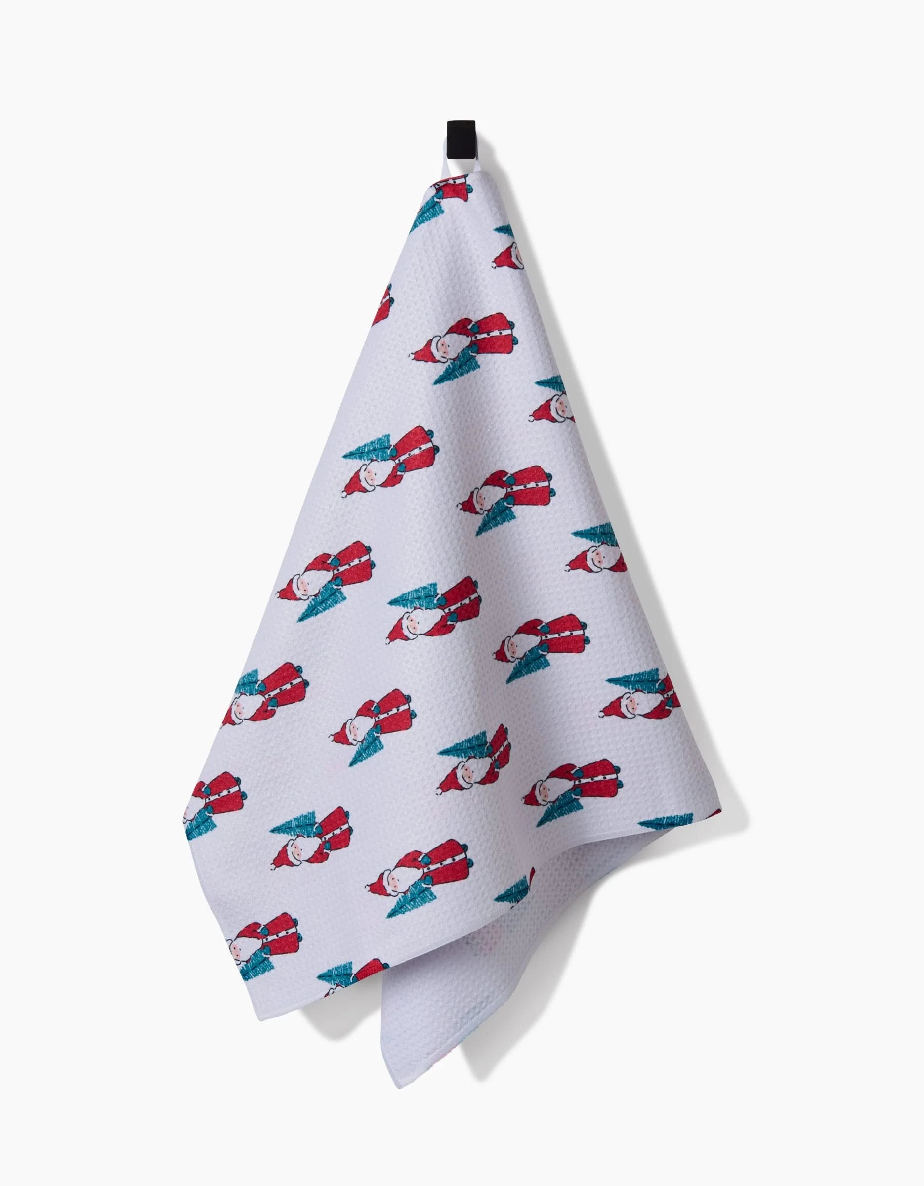 The Little Santa kitchen towel by Hufton Studio hangs on a hook, showcasing cartoon Santas with green presents in festive red, white, and blue colors. Made from recycled materials.