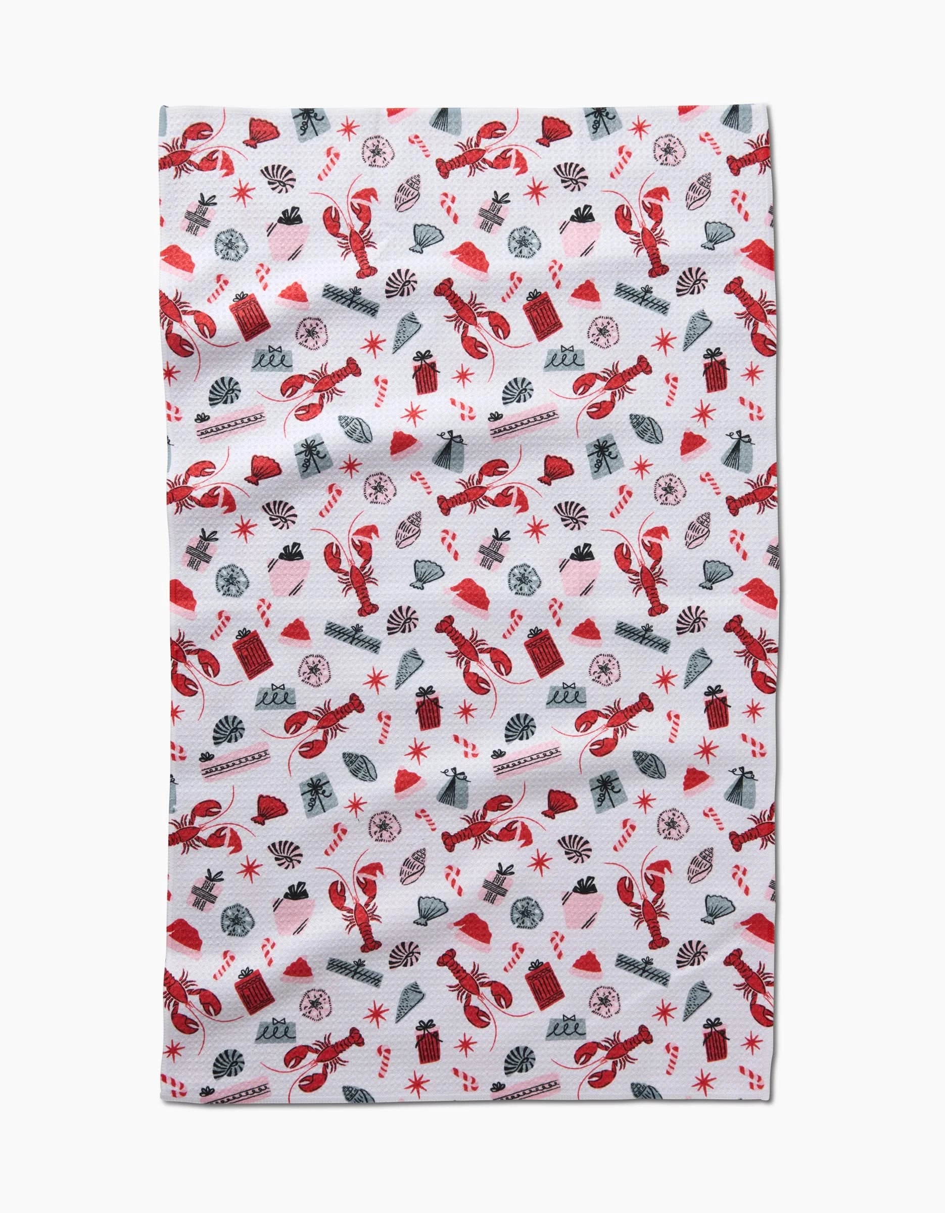The Lobster Holiday tea towel by Charlie Rowan Designs is white and decorated with a festive pattern of red and gray candy canes, gifts, snowflakes, bows, ornaments, and holly leaves.