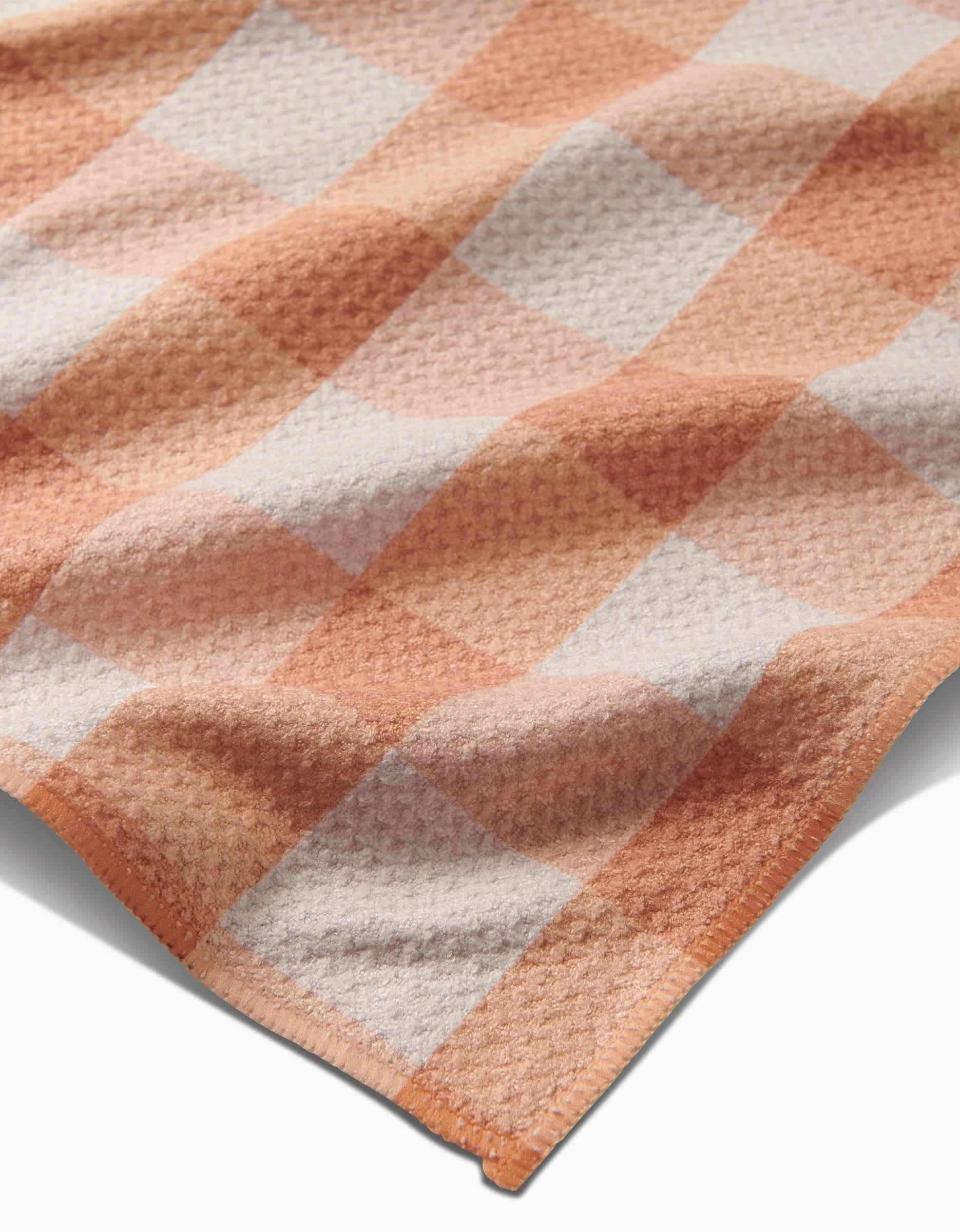 A close-up of the Lorraine tea towel by Kelsi Fullmer, showcasing its orange and white checkered Geoweave fabric with a soft, textured weave and neatly finished edges.