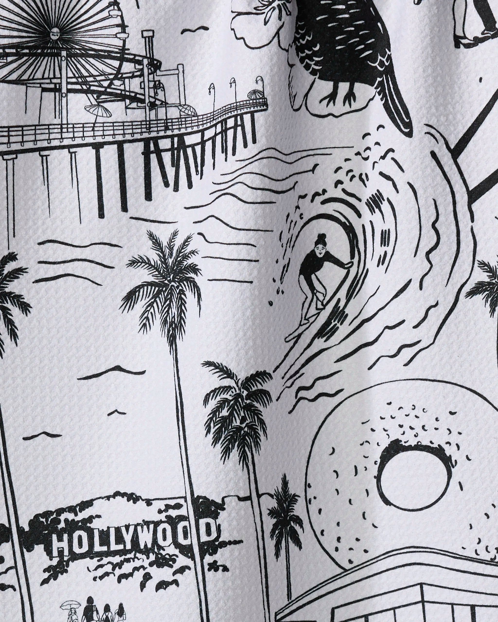 This absorbent dish towel by Elisabeth Wing, named "Los Angeles," features a black-and-white illustration of a surfer, palm trees, a pier ferris wheel, the Hollywood sign, and a donut—iconic scenes from California.
