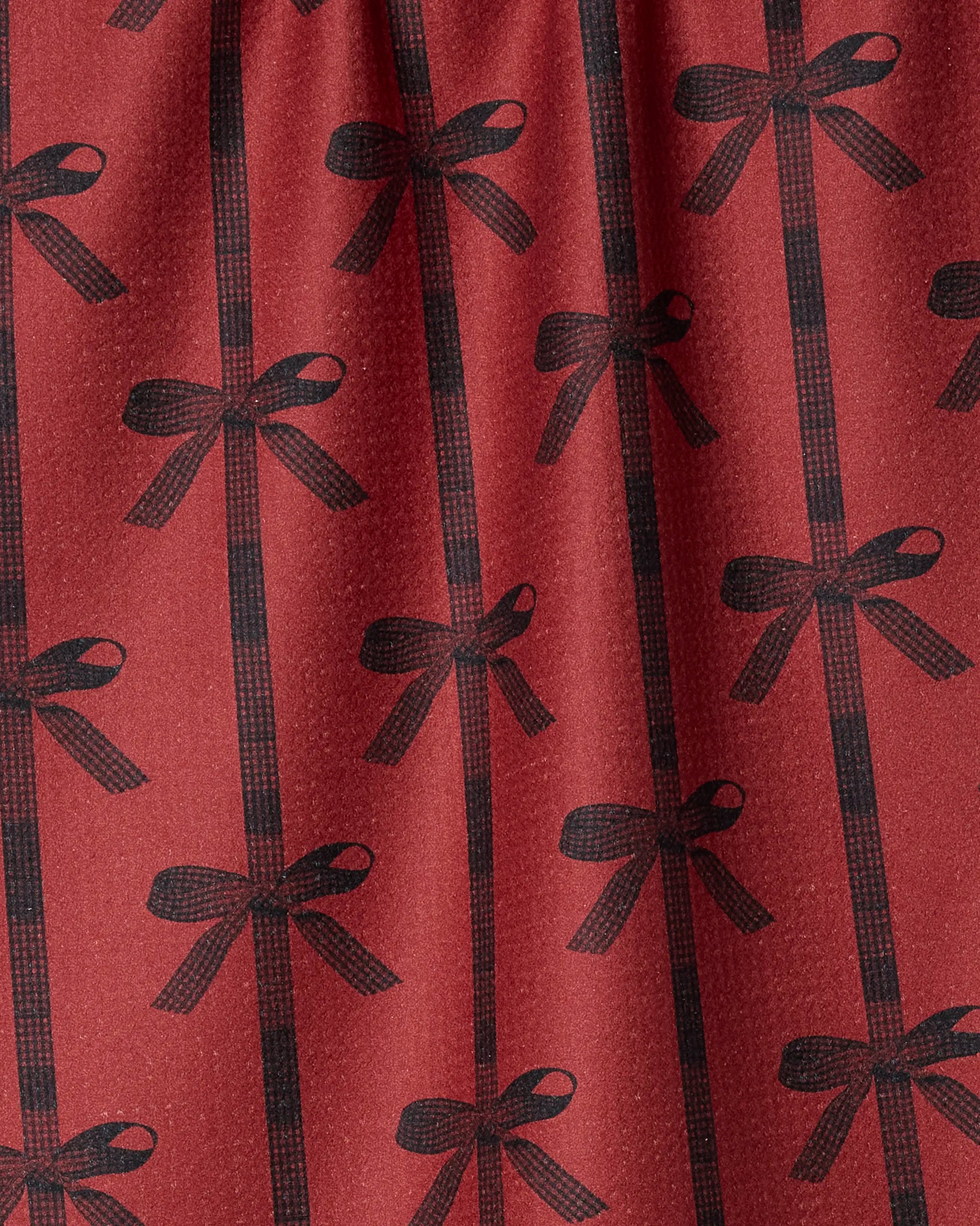 Love Bows by Geometry features red fabric with a repeating black bow pattern and vertical lines, creating a gift-wrapped look—ideal for an eco-friendly tea towel to add cheerful style to your kitchen.