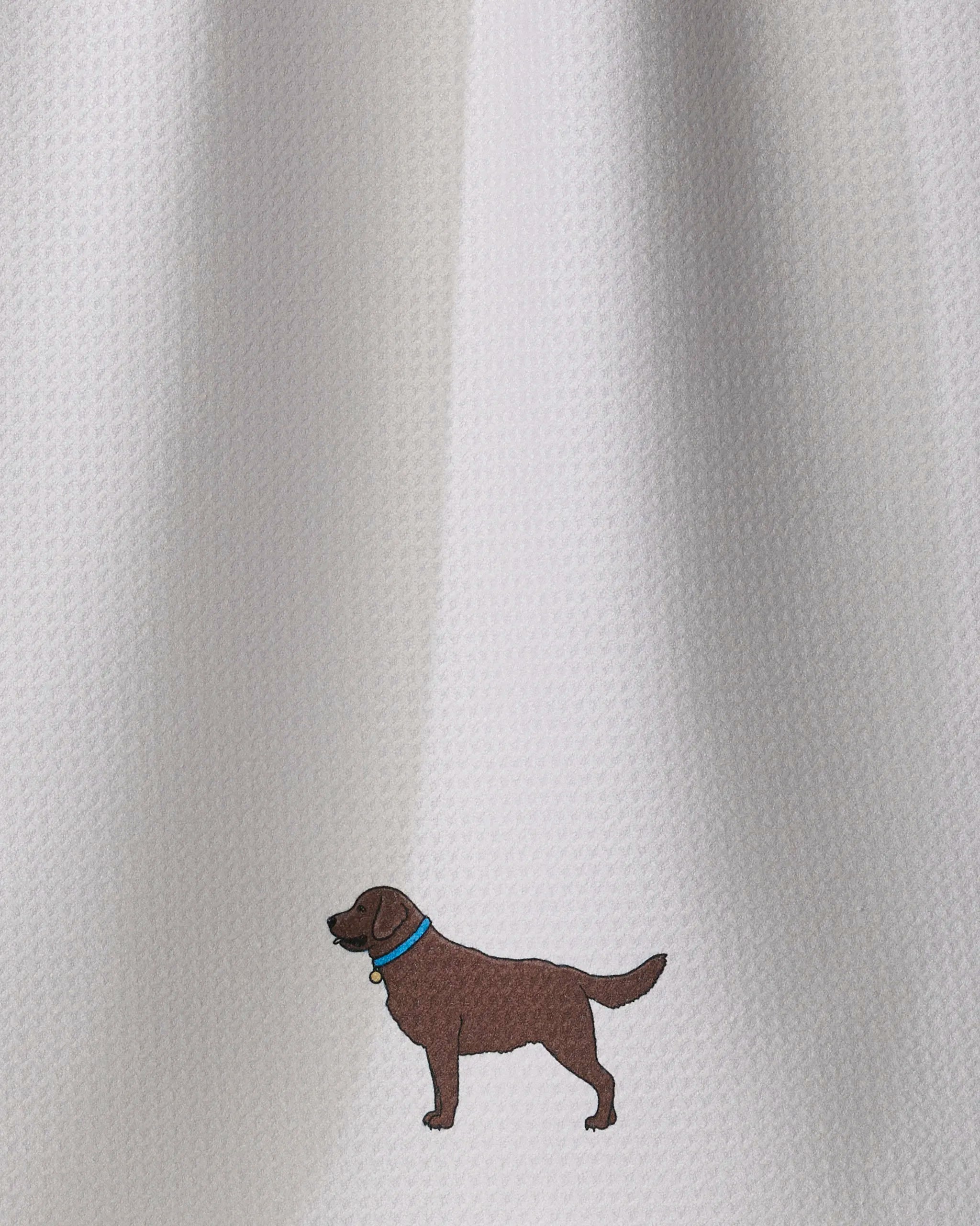 A small embroidered brown dog with a blue collar, called Loyal Lab by Geometry, sits on a textured white fabric background crafted from an ultra-absorbent tea towel.