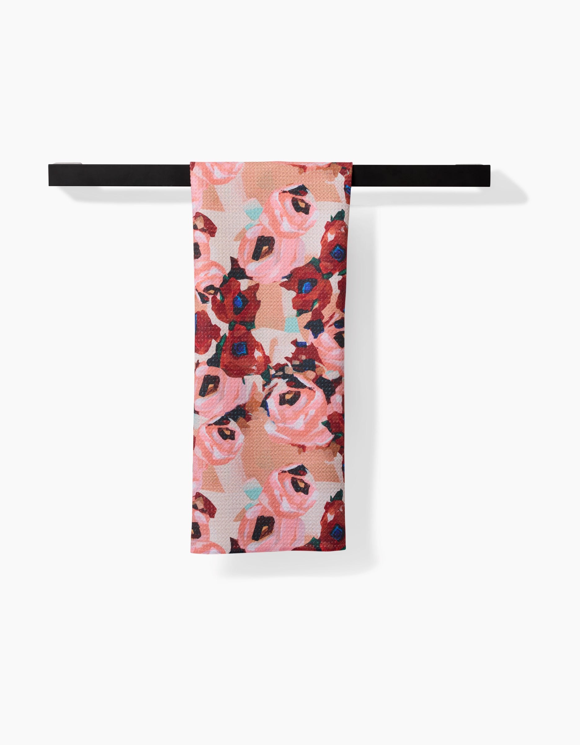 The Lucia Tea Towel by Ania Zwara Art features pink and red roses with green leaves, hanging over a black towel bar. Made from Geoweave™ fabric, it offers enhanced softness and durability against a white background.