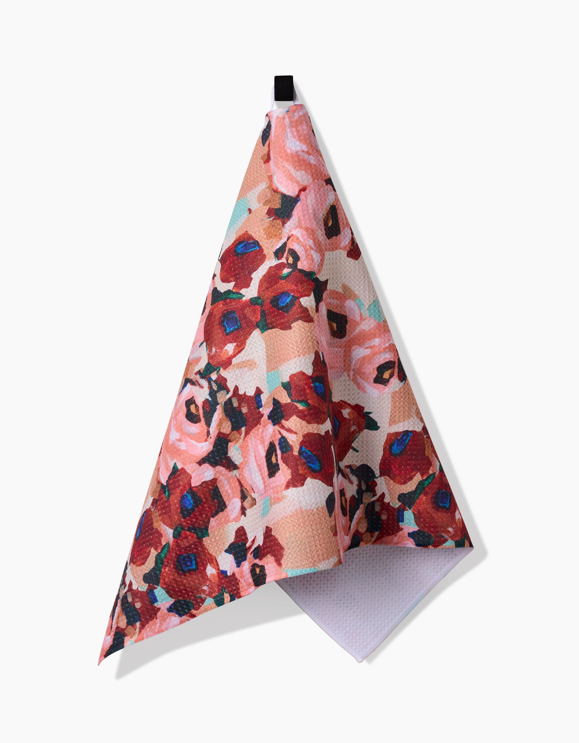 The Lucia Tea Towel by Ania Zwara Art features a vibrant floral pattern in red, pink, and blue, hangs from a black loop against a white background, and is crafted from sustainable recycled materials.