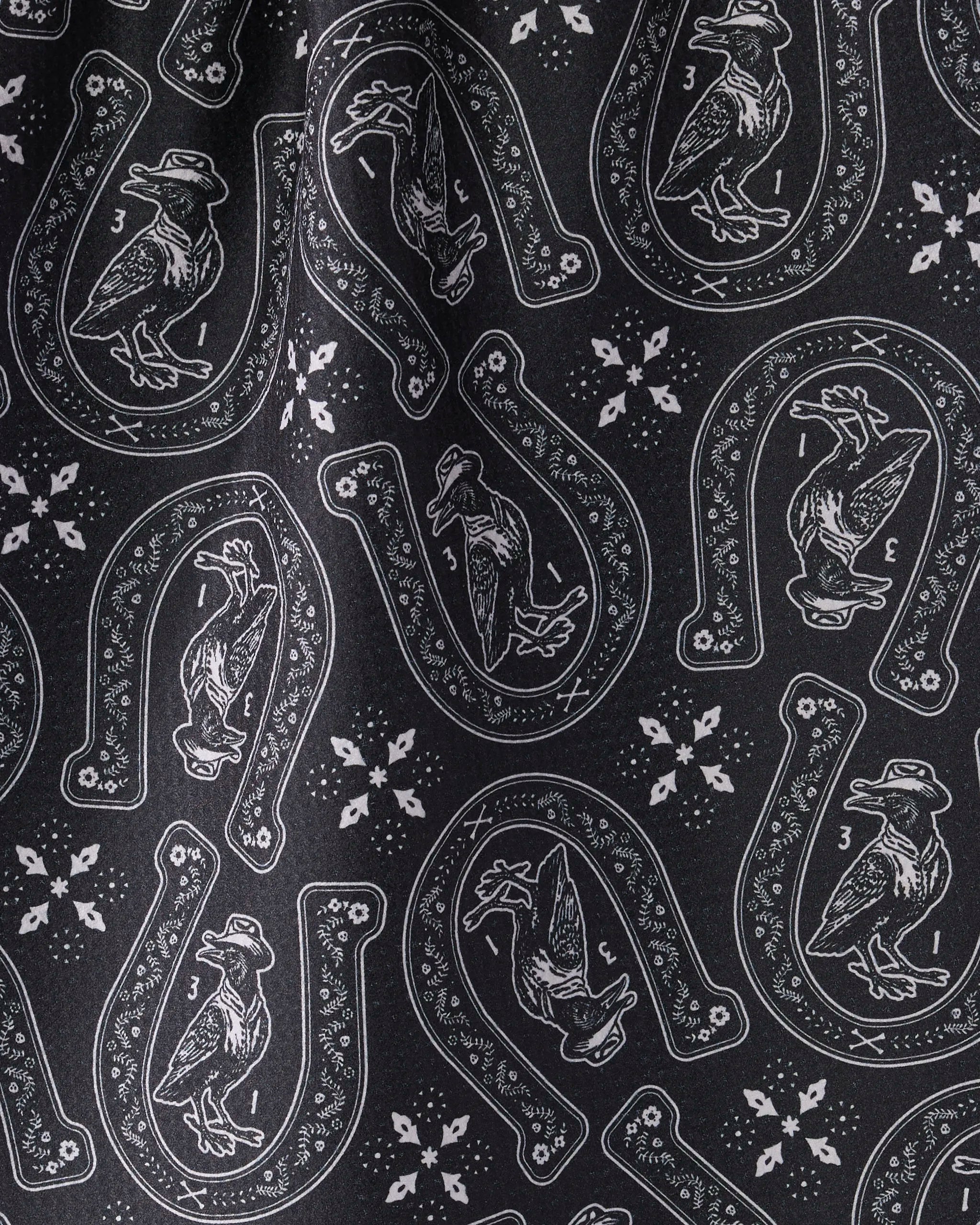 The Geometry Lucky Crow kitchen towel features black fabric with white horseshoes and birds in hats, plus small snowflakes. Ultra-absorbent and stylish, it’s perfect for daily use.
