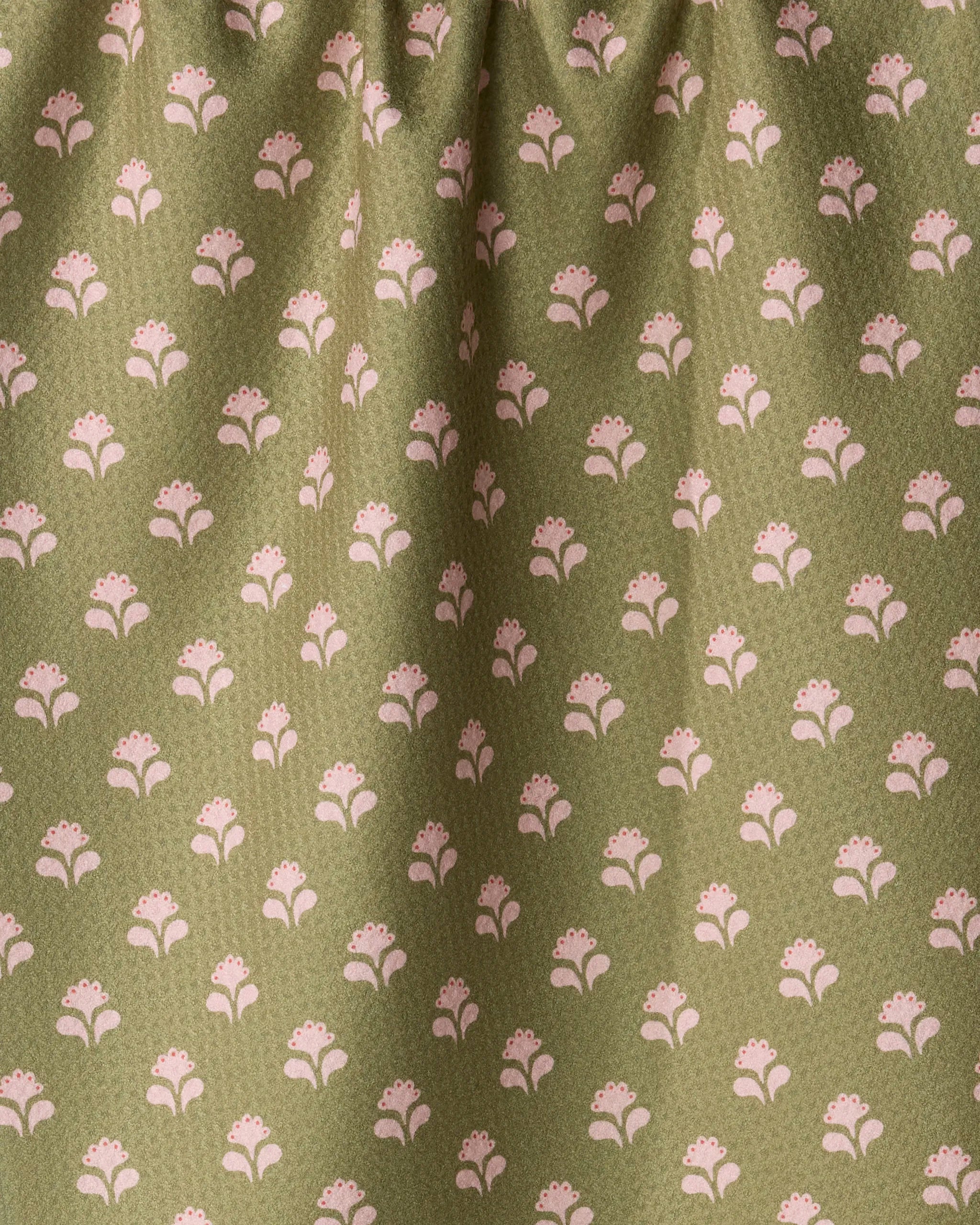 A close-up of folded olive green fabric from Geometry’s “Lucky Flowers” collection, crafted from recycled materials and showcasing a repeating grid of small, light pink stylized floral sprigs. The soft, slightly fuzzy texture makes it perfect for an ultra-absorbent kitchen tea towel.