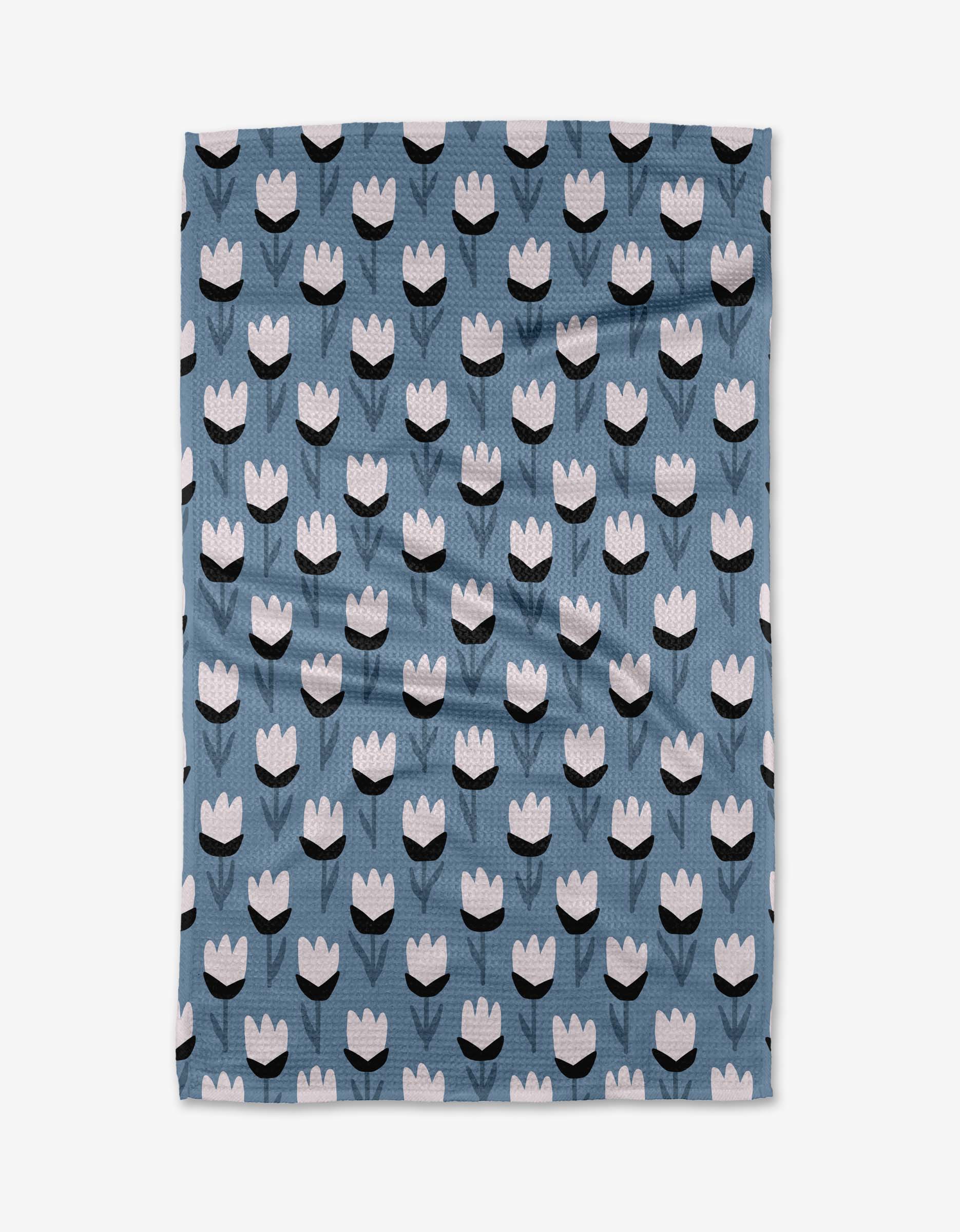 The Lush Meadow tea towel by Anette Heiberg features white and black tulip-like flowers in rows on blue Geoweave fabric—ultra-absorbent for both style and function.