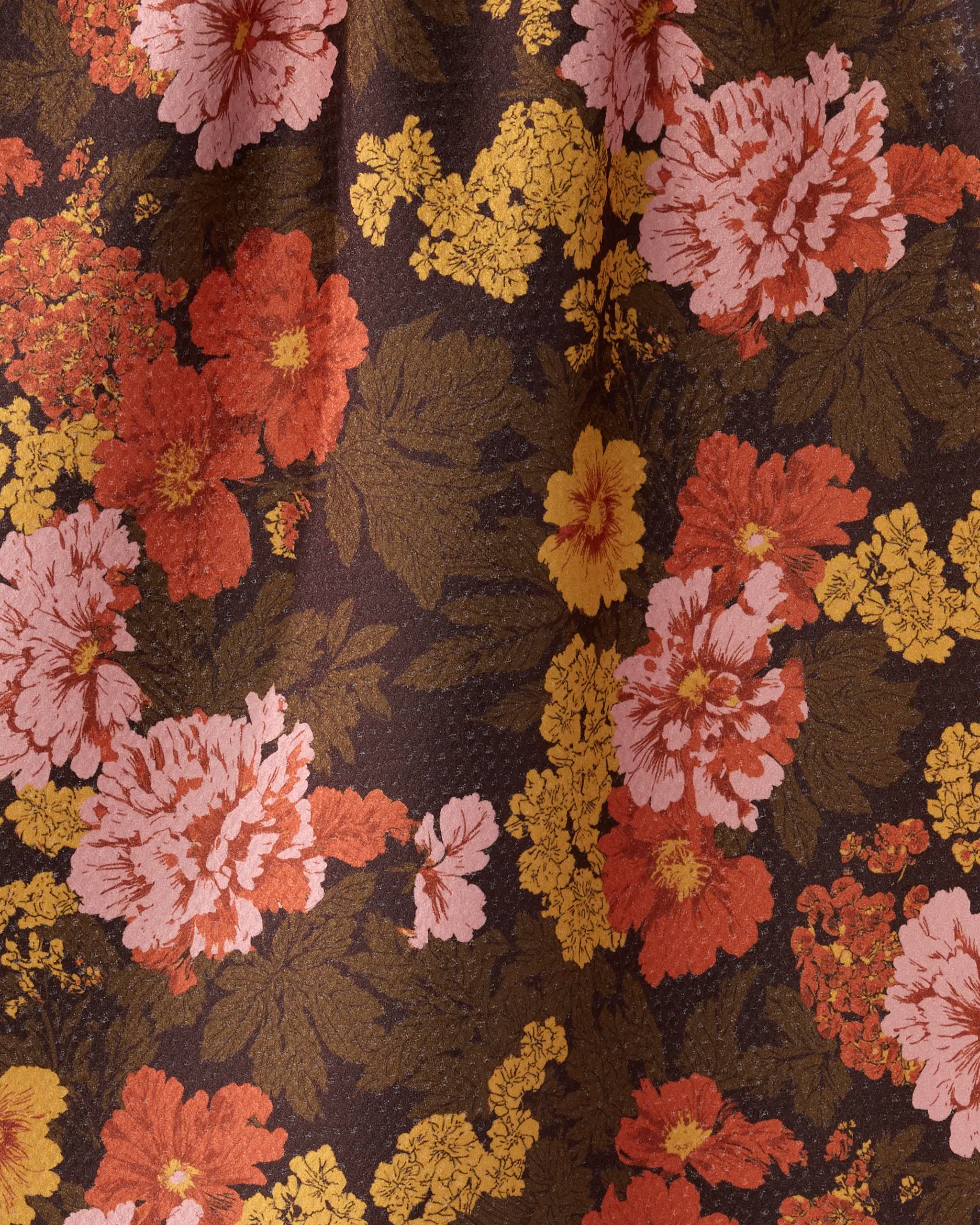 A close-up of Geometry’s Mabel tea towel shows ultra-absorbent, recycled fabric with a textured surface and large pink, orange, and yellow flowers with green leaves on a dark brown background.