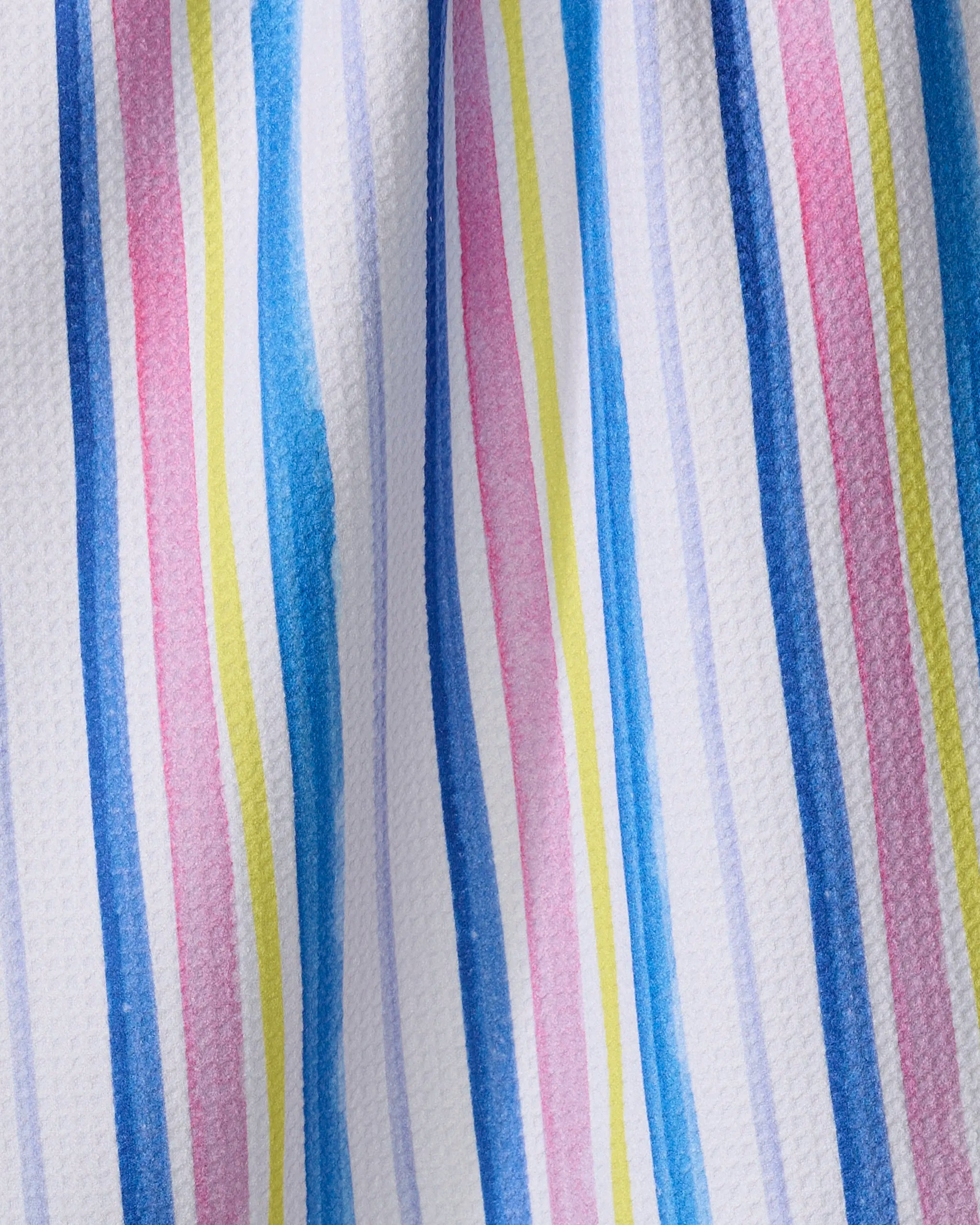 The Macarons in Paris Stripe tea towel by Travel Write Draw (Meagan Morrison) features hand-painted style blue, pink, yellow, and purple stripes on textured white fabric for a vibrant yet practical kitchen accent.