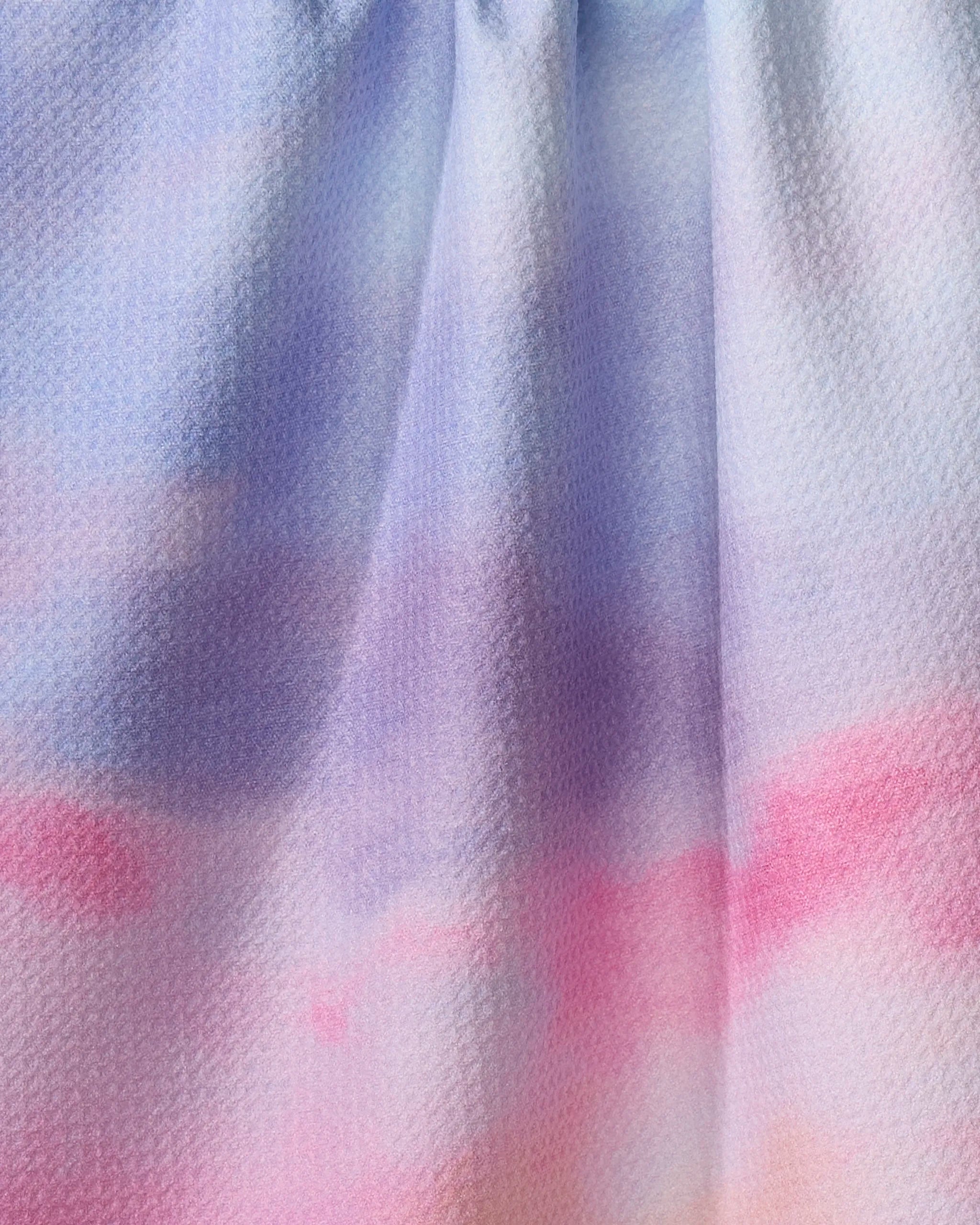 The Magic In The Sky dish towel by Stefanie Bales features an absorbent, textured fabric with a pastel gradient in blue, purple, pink, and peach tones, resembling a soft watercolor design.