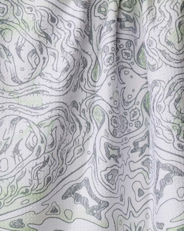 Close-up of the Manta tea towel by Skye Walker, crafted from recycled materials. Features a black and white abstract, symmetrical pattern with subtle green accents on softly folded, ultra-absorbent fabric.