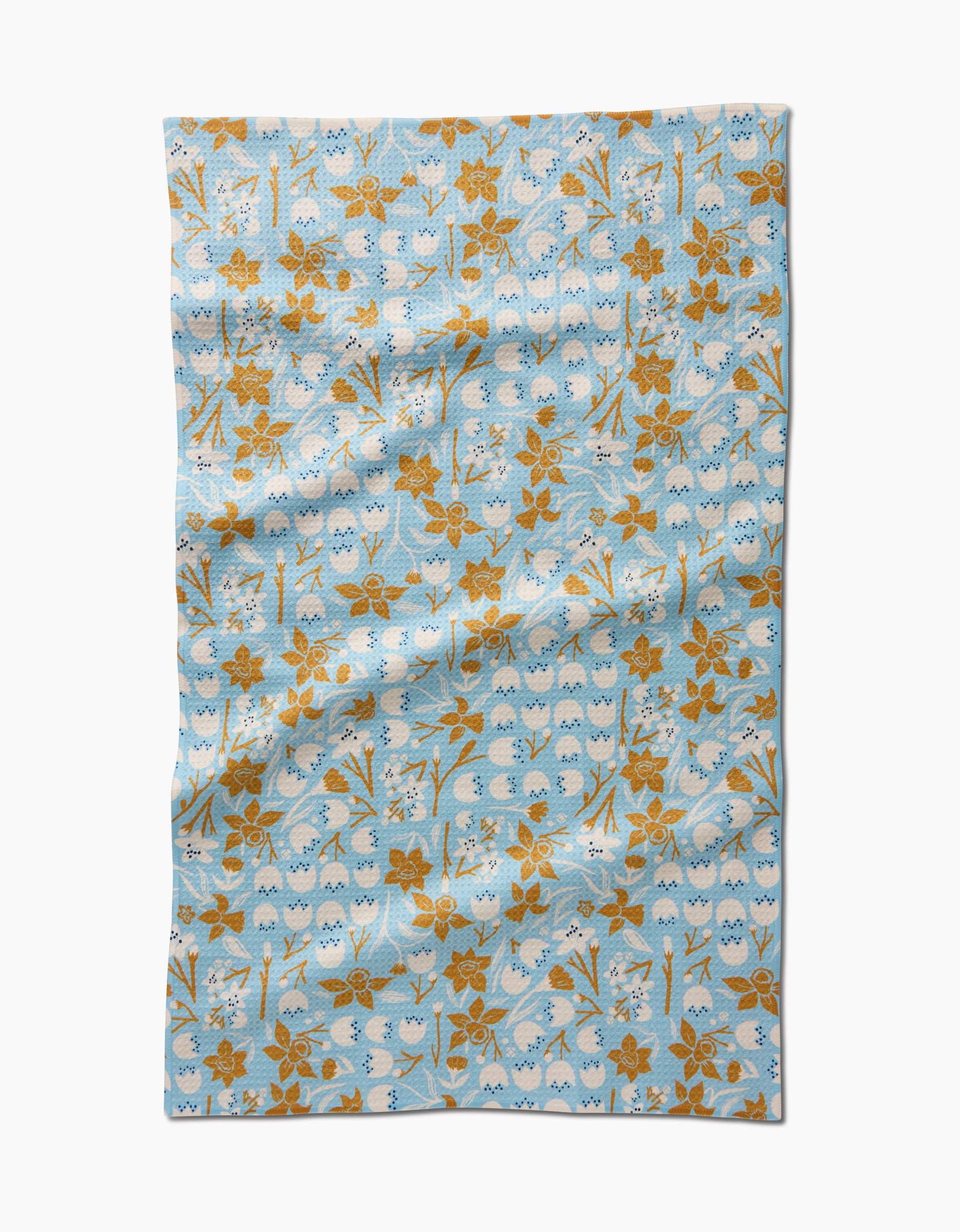 The March Tea Towel by Elisabeth Wing features a light blue background with an orange-brown floral pattern and white accents. Made from Geoweave™ fabric, it has a slightly wrinkled look and is set against a white backdrop.