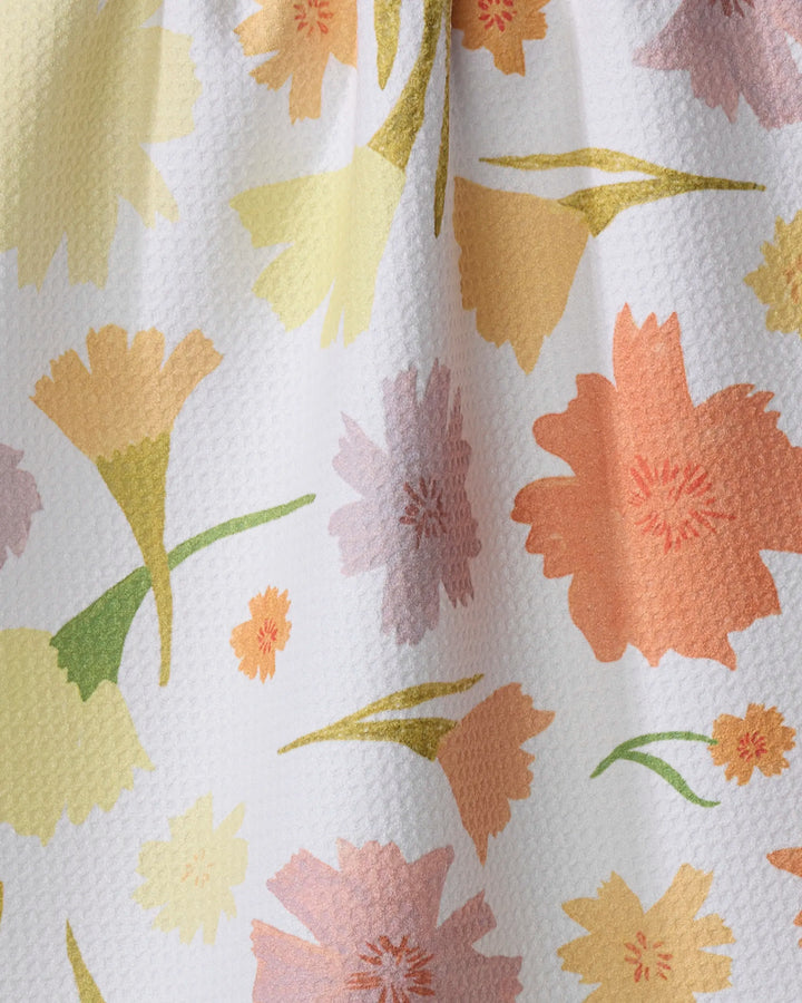 A close-up of Elana Gabrielle’s Marigold Flowers kitchen towel, ultra-absorbent with a textured surface and a vibrant floral pattern in yellow, orange, pink, and green on a white background.