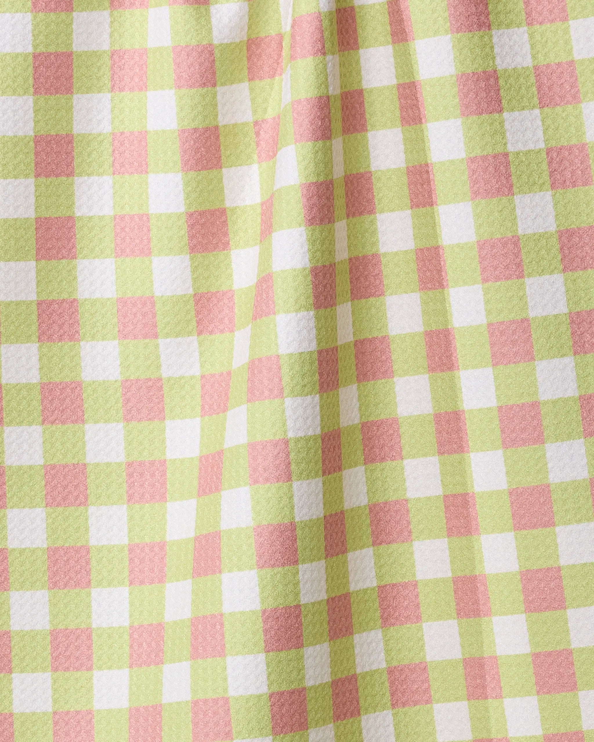 A close-up of the Mariquita Gingham kitchen towel by Geometry, featuring a pastel green, pink, and white gingham checkered pattern with a soft drape and textured surface.