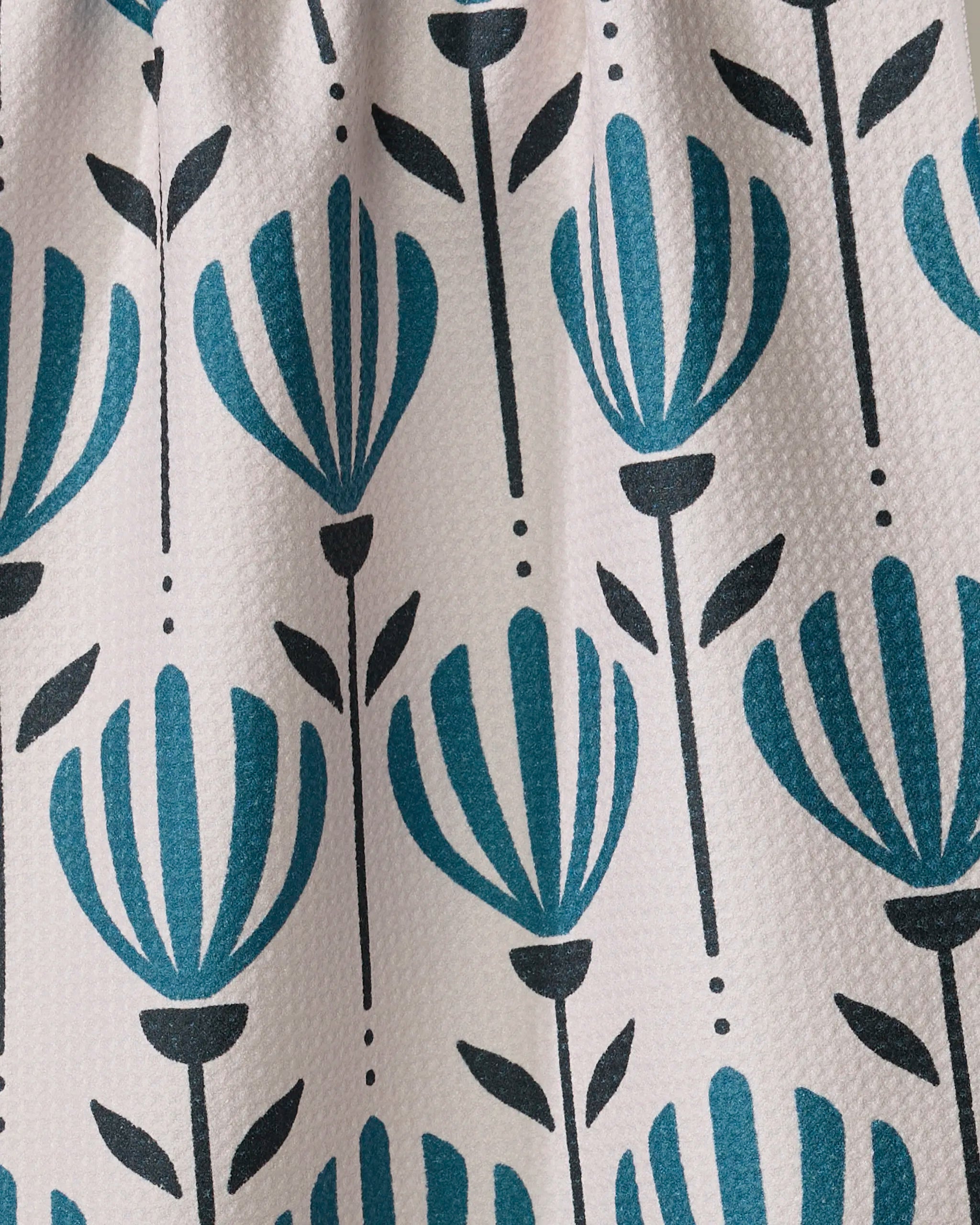 Close-up of Martine by Amy MacCready: recycled kitchen towel fabric with blue and black stylized flowers, vertical stems, and small leaves on a white textured background.