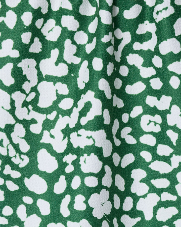 The Mas Feroz dish towel by Geometry features a green fabric with an abstract white leopard print, a slightly textured, absorbent surface, and irregular white spots across the background.