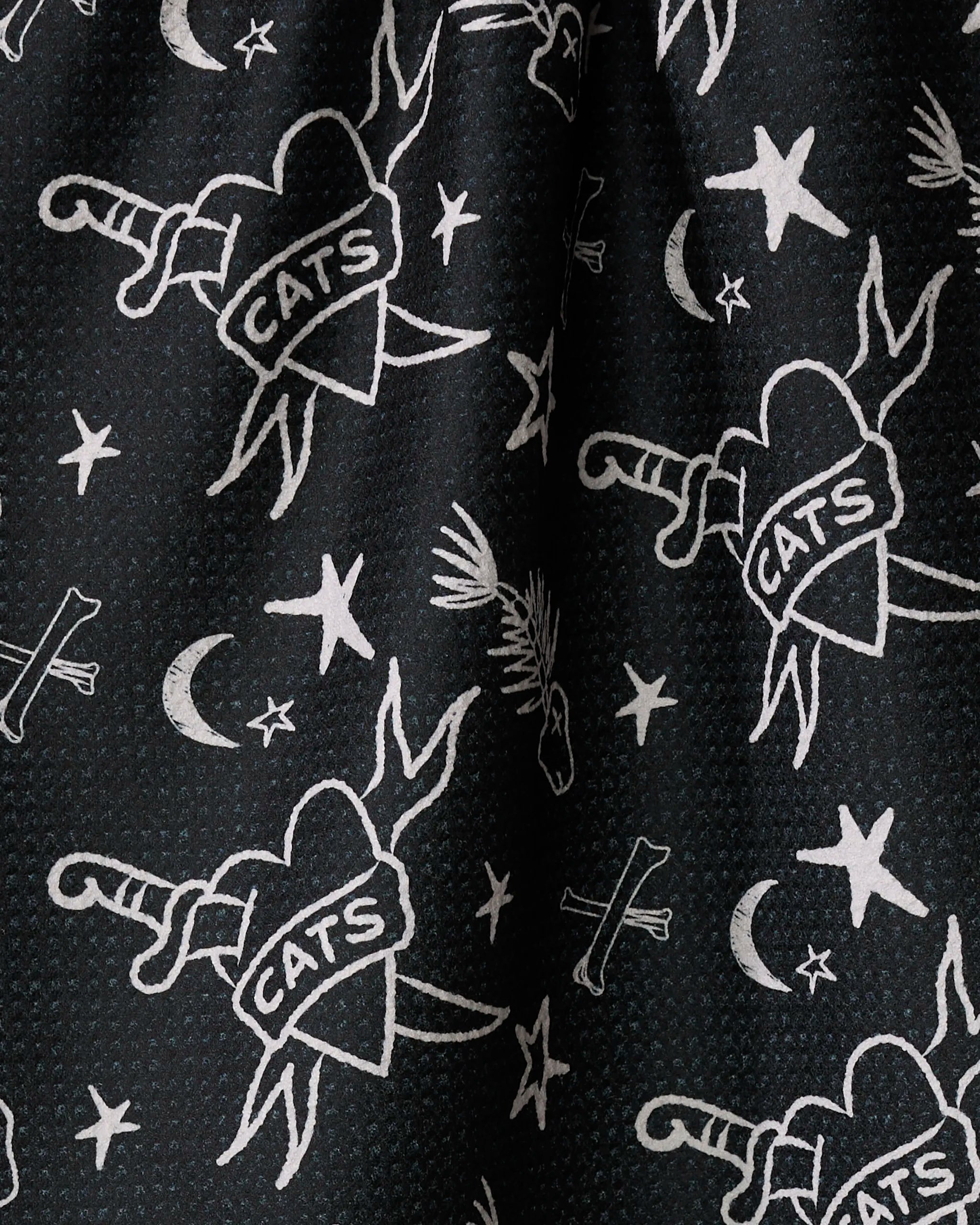 The "Meow or Never" tea towel by Cole Strem features black Geoweave fabric with white tattoo-style hearts labeled CATS, pierced by daggers, plus stars, moons, and bones—a unique addition to any kitchen.