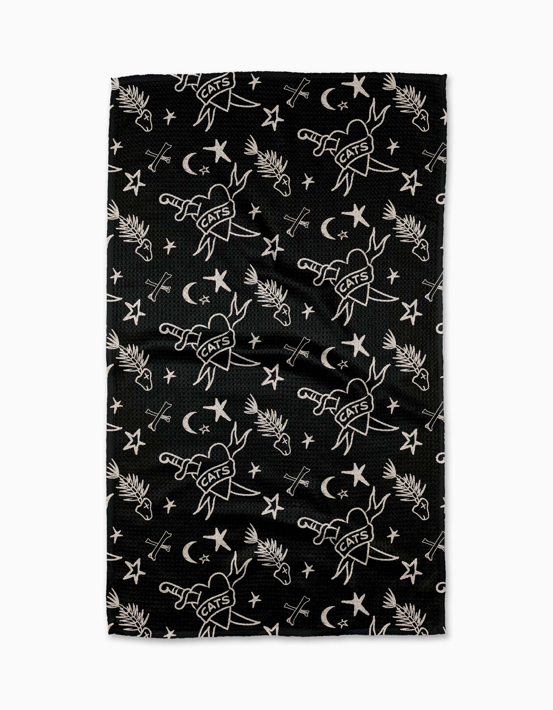 The Meow or Never Tea Towel by Cole Strem is a black Geoweave towel made from recycled materials, featuring white illustrations of swords labeled CATS, crescent moons, stars, palm leaves, and crossed arrows.