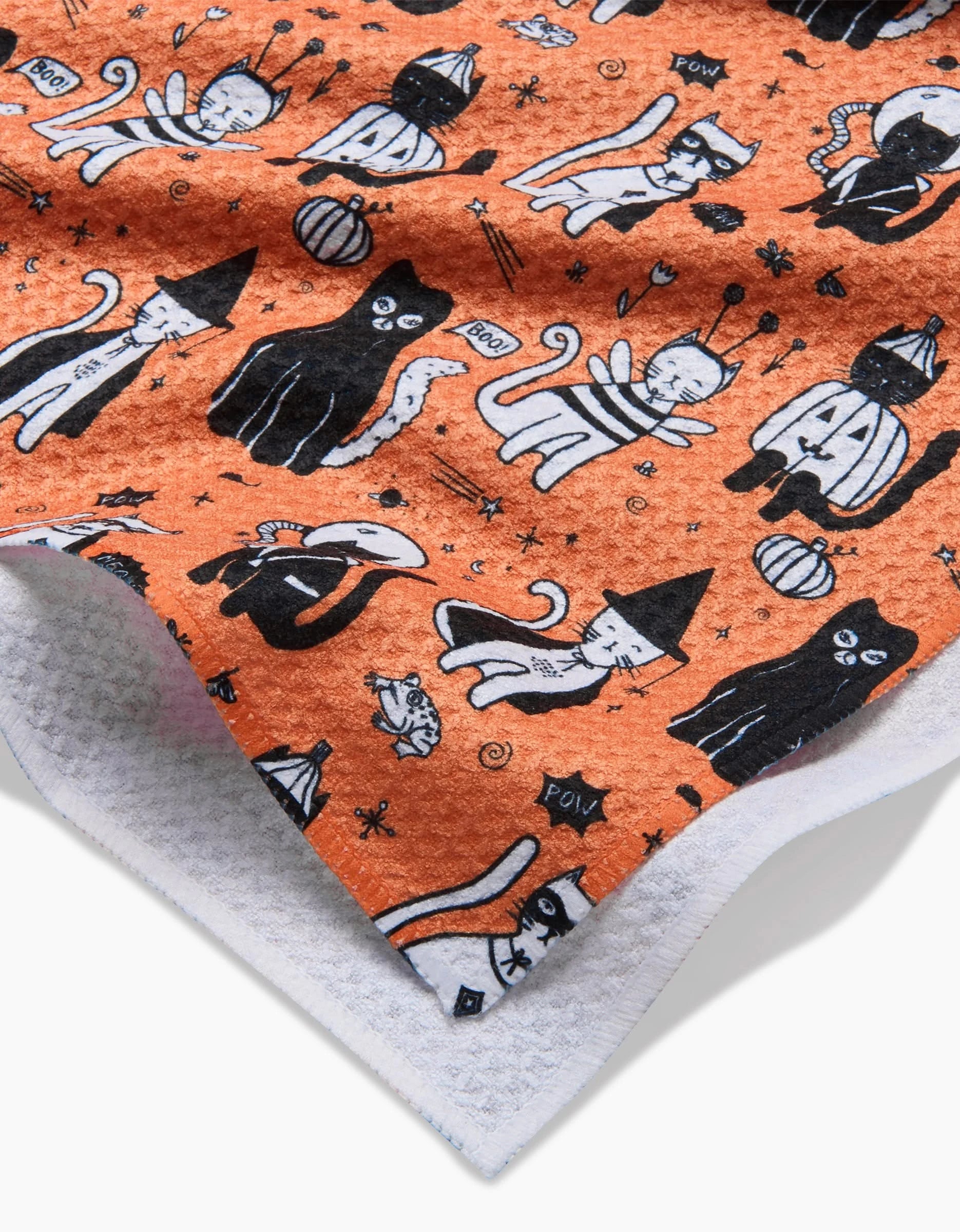 The Meowlloween tea towel by Elisabeth Wing is ultra-absorbent and orange, featuring Halloween cats in hats, masks, and capes with stars, pumpkins, and “POW!”—a playful pick for seasonal fun.