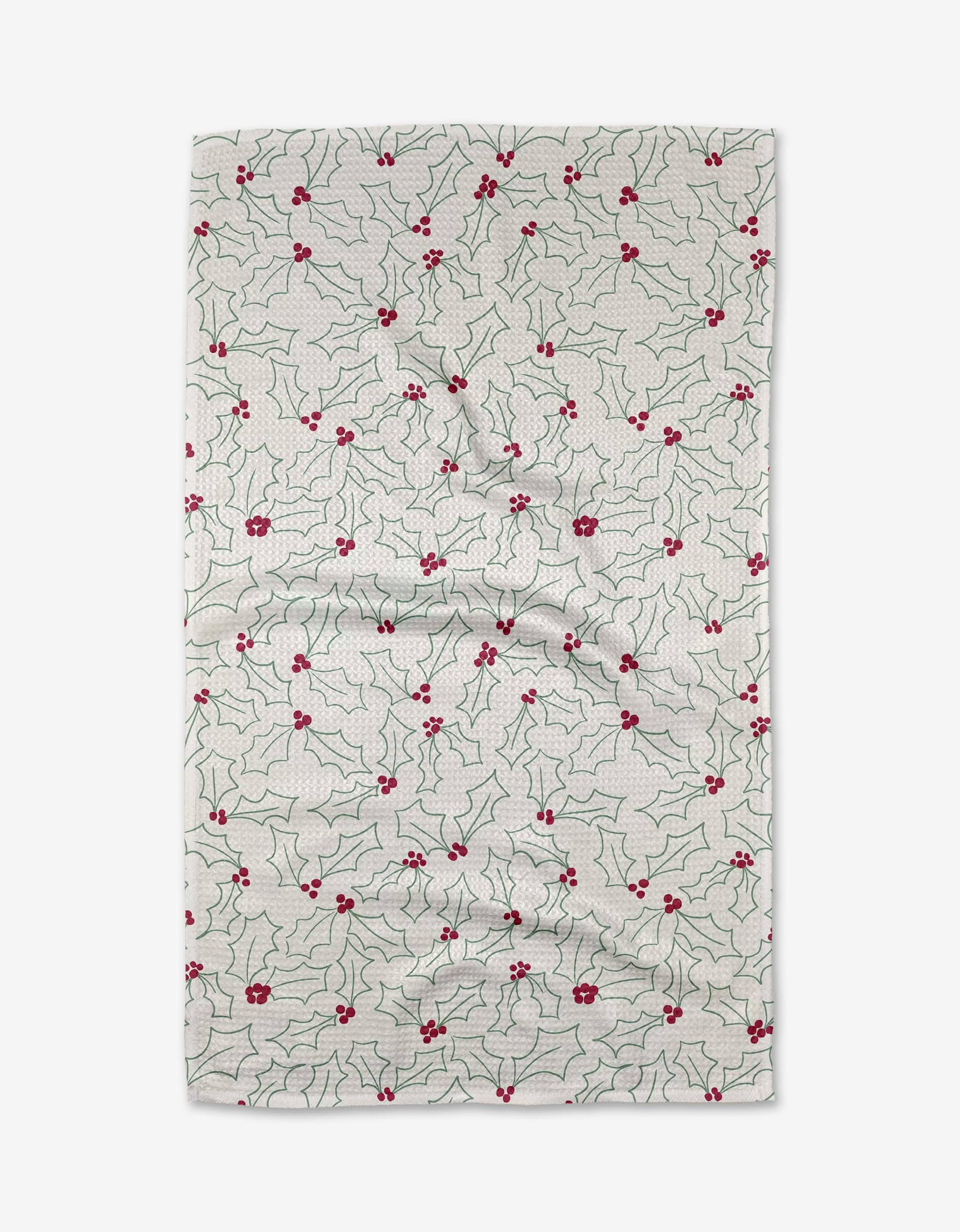 The Kayla Ann Merry Holly kitchen towel, made from recycled materials, features green holly leaves and red berries on white fabric. Lightly wrinkled, it is displayed on a plain white background.