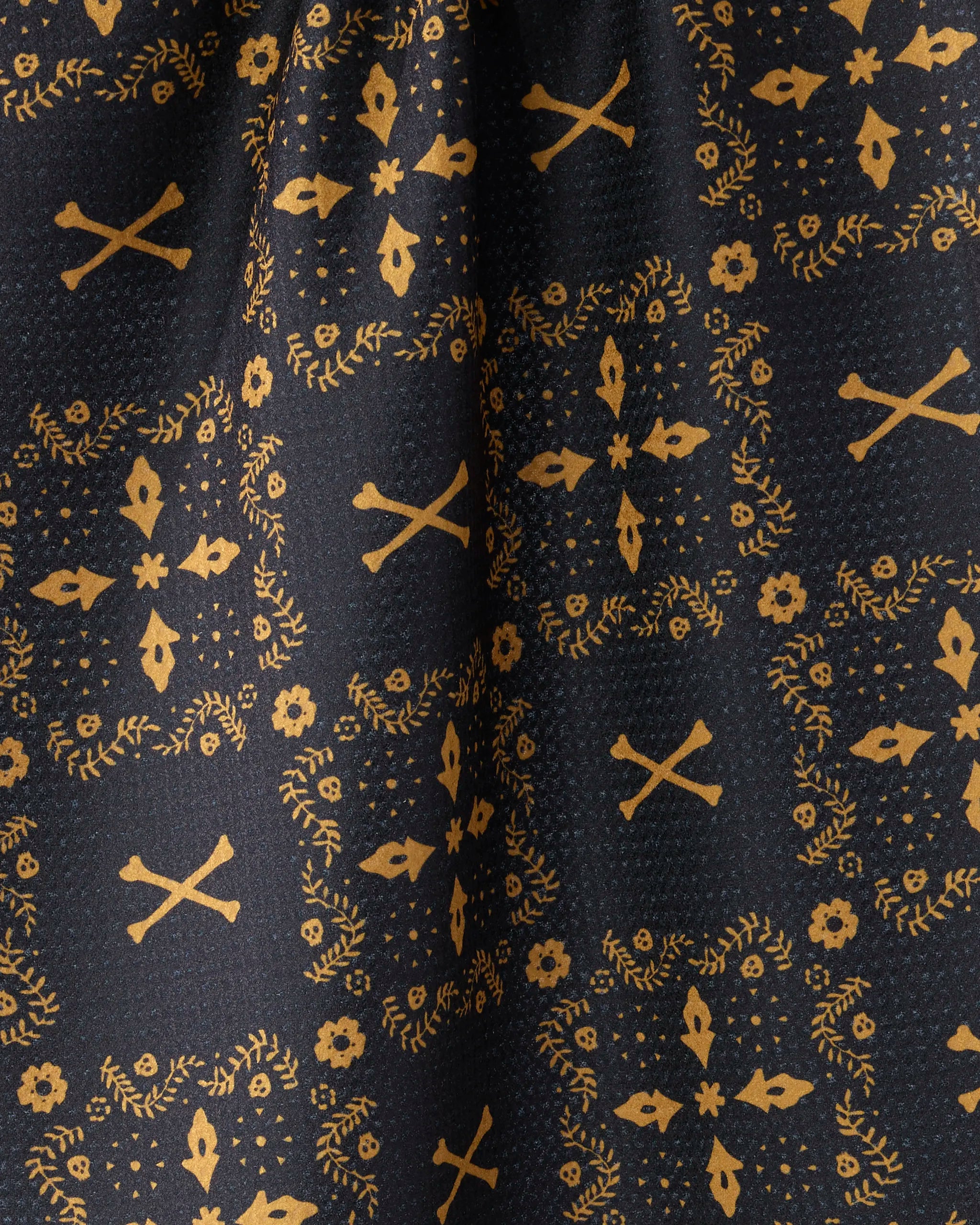 Close-up of Geometry's Midnight Bandana: a black tea towel with a yellow, paisley-inspired pattern featuring small florals, leafy branches, and X motifs—absorbent and made from recycled materials.