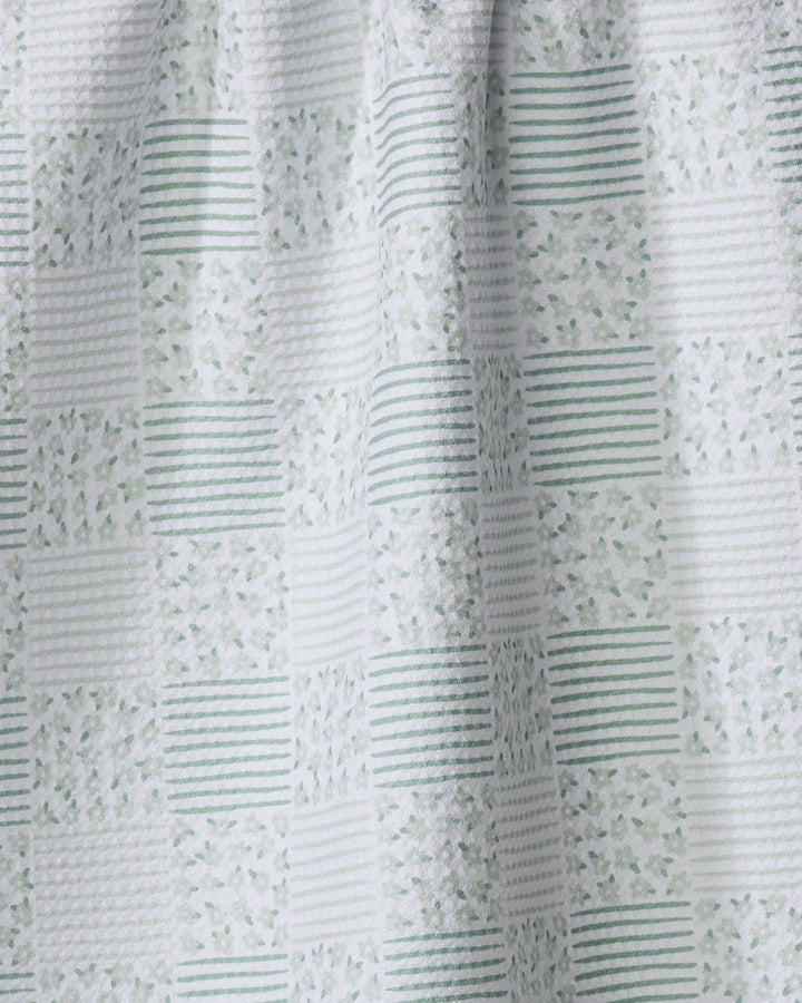 A close-up of Hufton Studio's Mini Flowers and Stripes Check Green tea towel fabric, showcasing a quick-drying textured checkerboard pattern with alternating green stripes and small floral motifs on a white background.