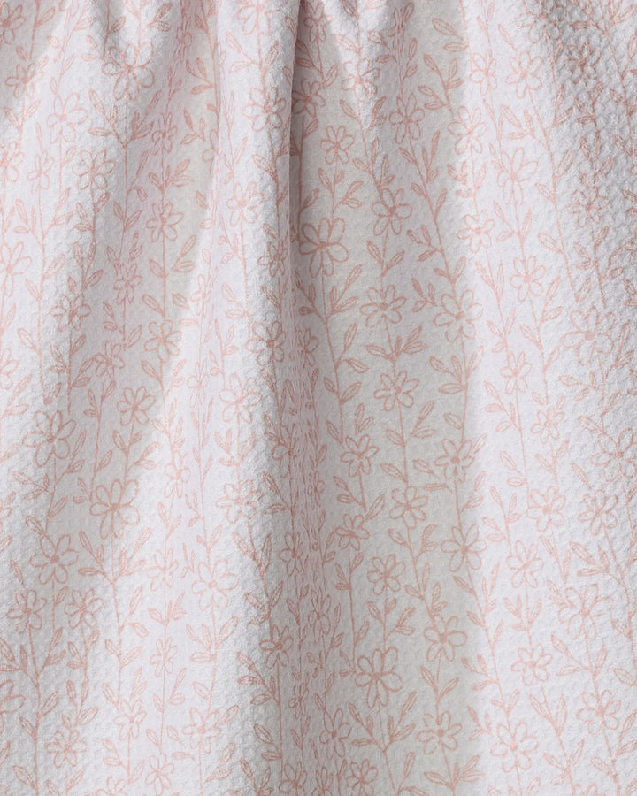 The Minimalist Blush tea towel by Teri the Butter features light pink fabric with a delicate floral pattern and thin stems. Quick-drying and softly gathered at the top, it’s textured and perfect for everyday use.