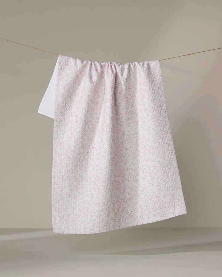 The Minimalist Blush tea towel by Teri the Butter, crafted from recycled materials, features a subtle pink botanical pattern and hangs neatly against a neutral background.