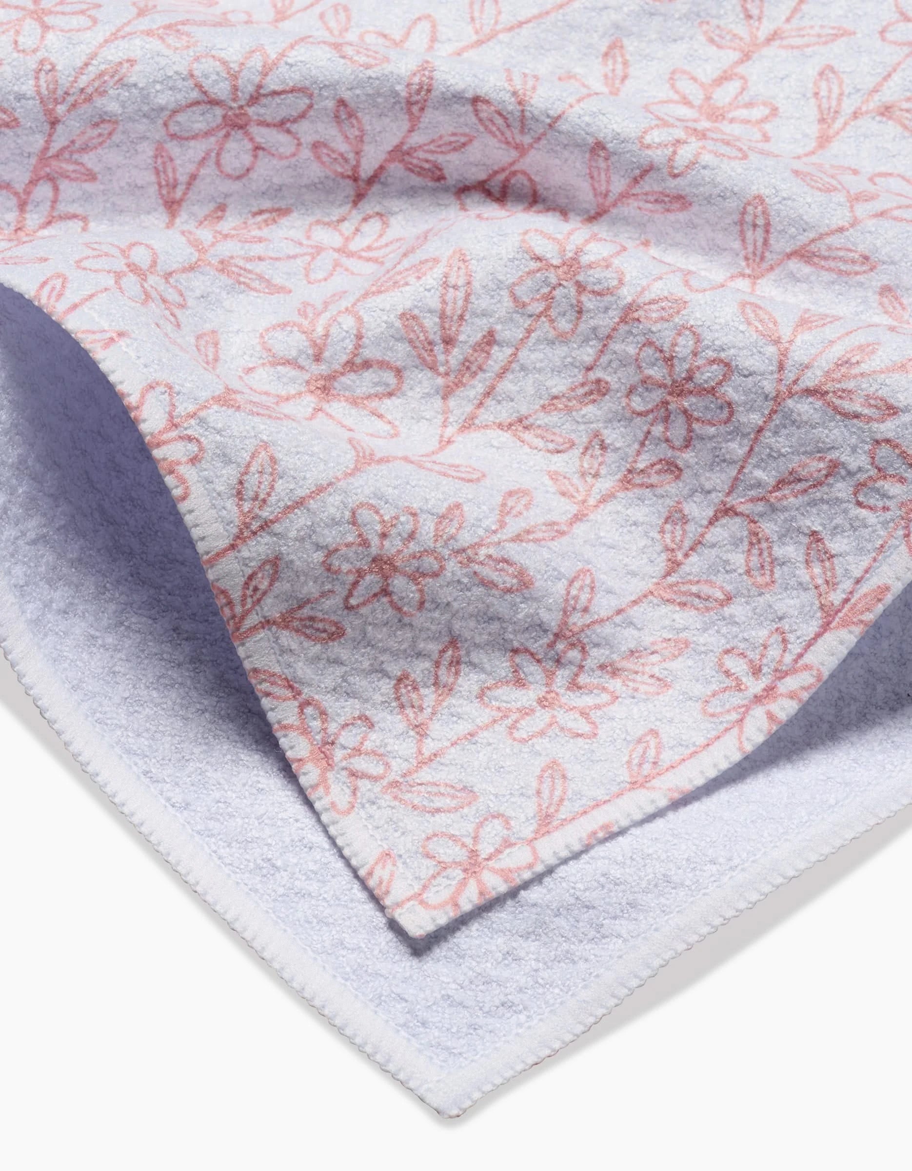 Close-up of Teri the Butter’s Minimalist Blush Tea Towel, made from Geoweave fabric with a soft texture. One corner is folded to display both sides and features a subtle light pink floral pattern on white.