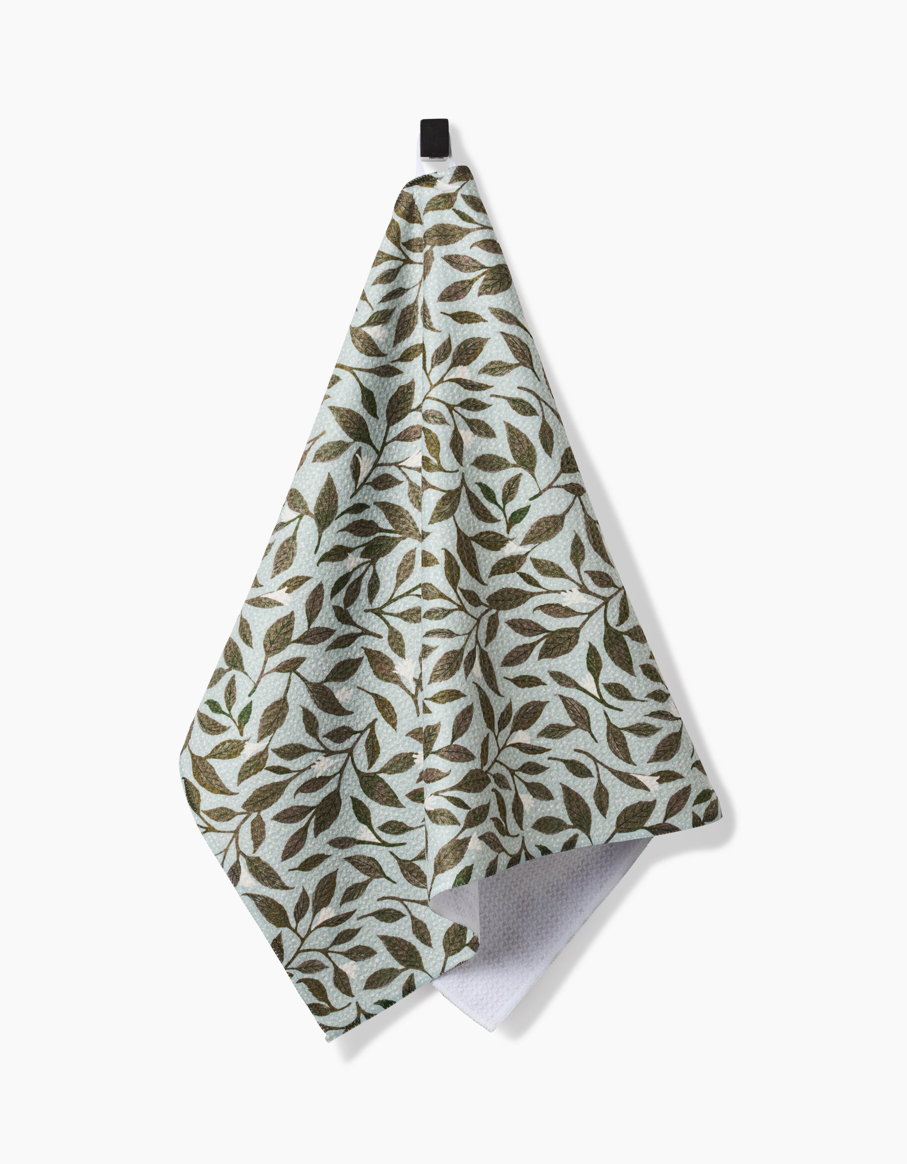 The Katie OShea Mint Leaves hanging tea towel, made from recycled materials, features a green and brown leafy design on a white background and is shown against a plain white surface.