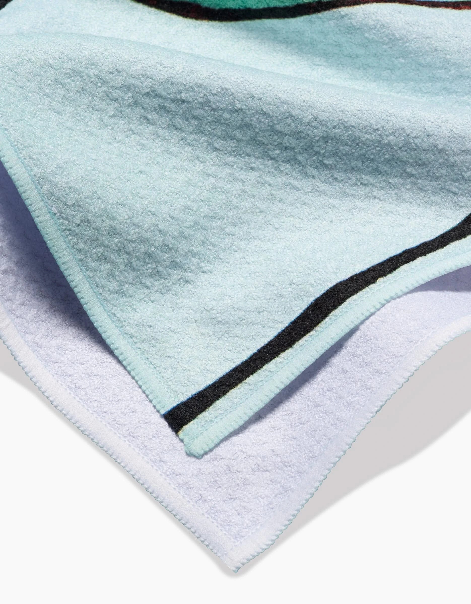 A close-up of the Rachel Austin Modern Poppy Tea Towel shows its textured Geoweave fabric, accented by a black and green stripe near the edge, neat trim, and a folded corner that reveals the soft underside.