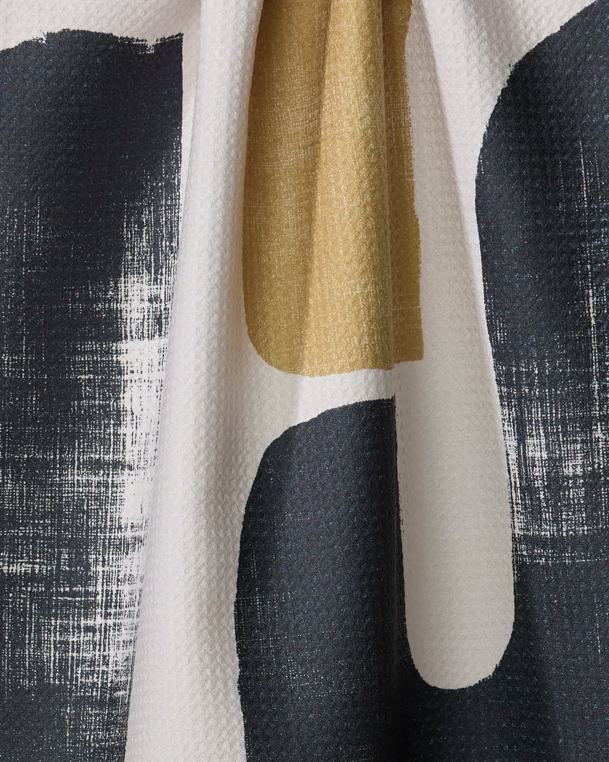 A close-up of the Mono tea towel by Geometry, featuring an abstract black, white, and mustard yellow pattern with brushstroke marks, crafted from recycled materials.