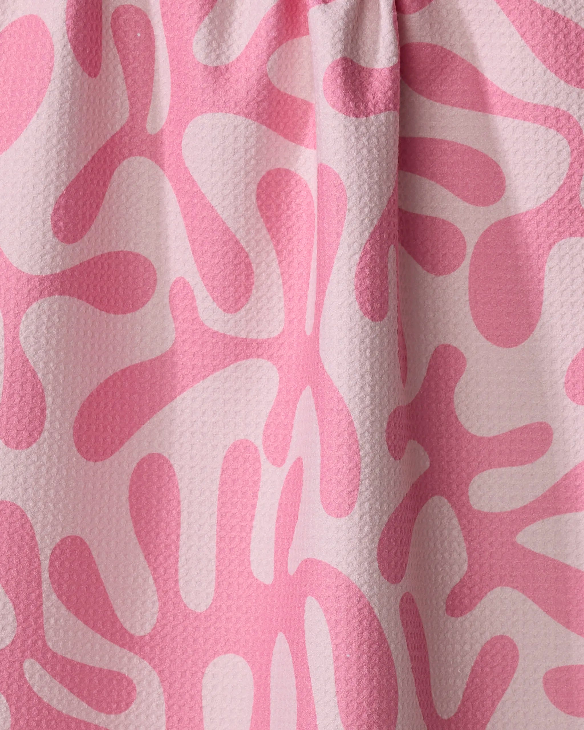 Close-up of Monochrome Morning by Marina Solodka, a quick-drying tea towel with textured fabric and an abstract organic pattern in light and dark pink wavy shapes scattered across the surface.