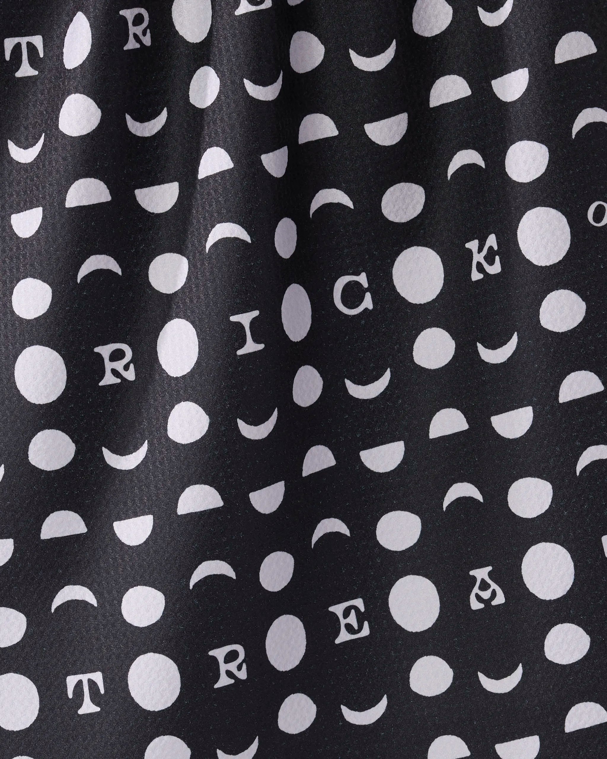 The Geometry Moonlit Mischief tea towel features black fabric with white dots, crescents, and "TRICK OR TREAT" lettering. Ultra-absorbent with a stylishly wrinkled look, it adds both charm and function to your kitchen.