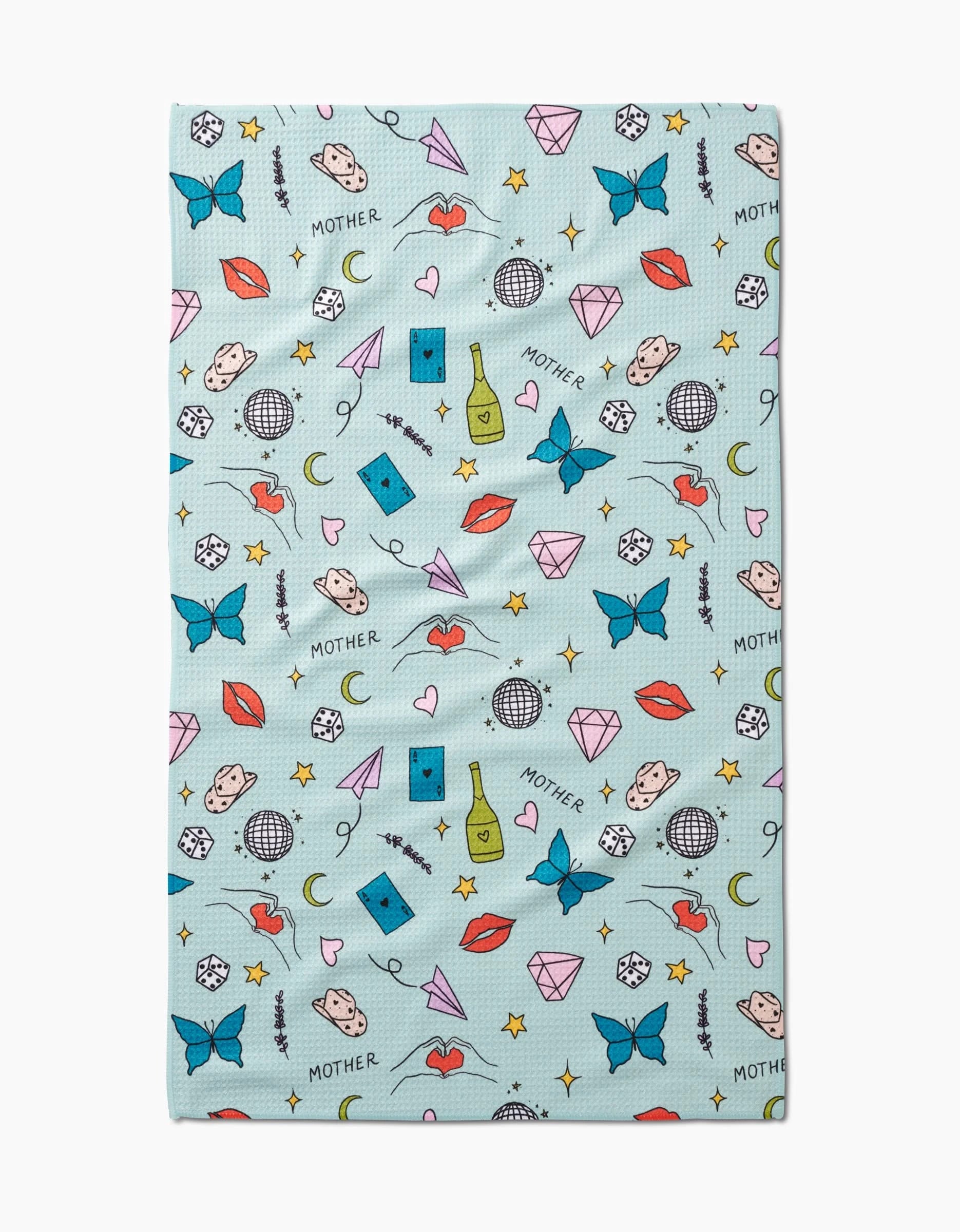 Mother by Sarah Holden is a light blue cloth crafted from recycled materials, featuring colorful illustrations like butterflies, diamonds, red lips, dice, hearts, disco balls, faces, wine bottles, stars, and the word MOTHER.