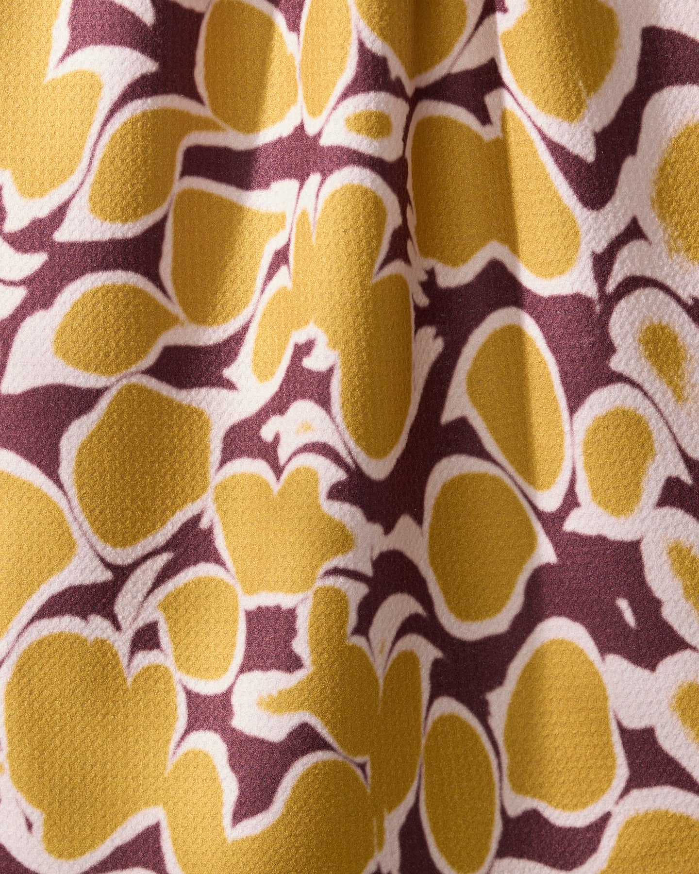 Geometry’s “Mottled” kitchen towel features a yellow and brown abstract floral pattern with organic shapes and irregular outlines on textured recycled fabric, creating a bold, lively look.