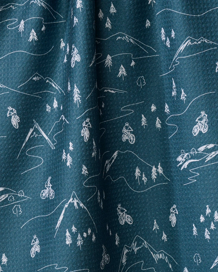 Coit Creative's "Mountain Biking" is a blue recycled kitchen towel with a white line art pattern of mountains, trees, and cyclists throughout the design.