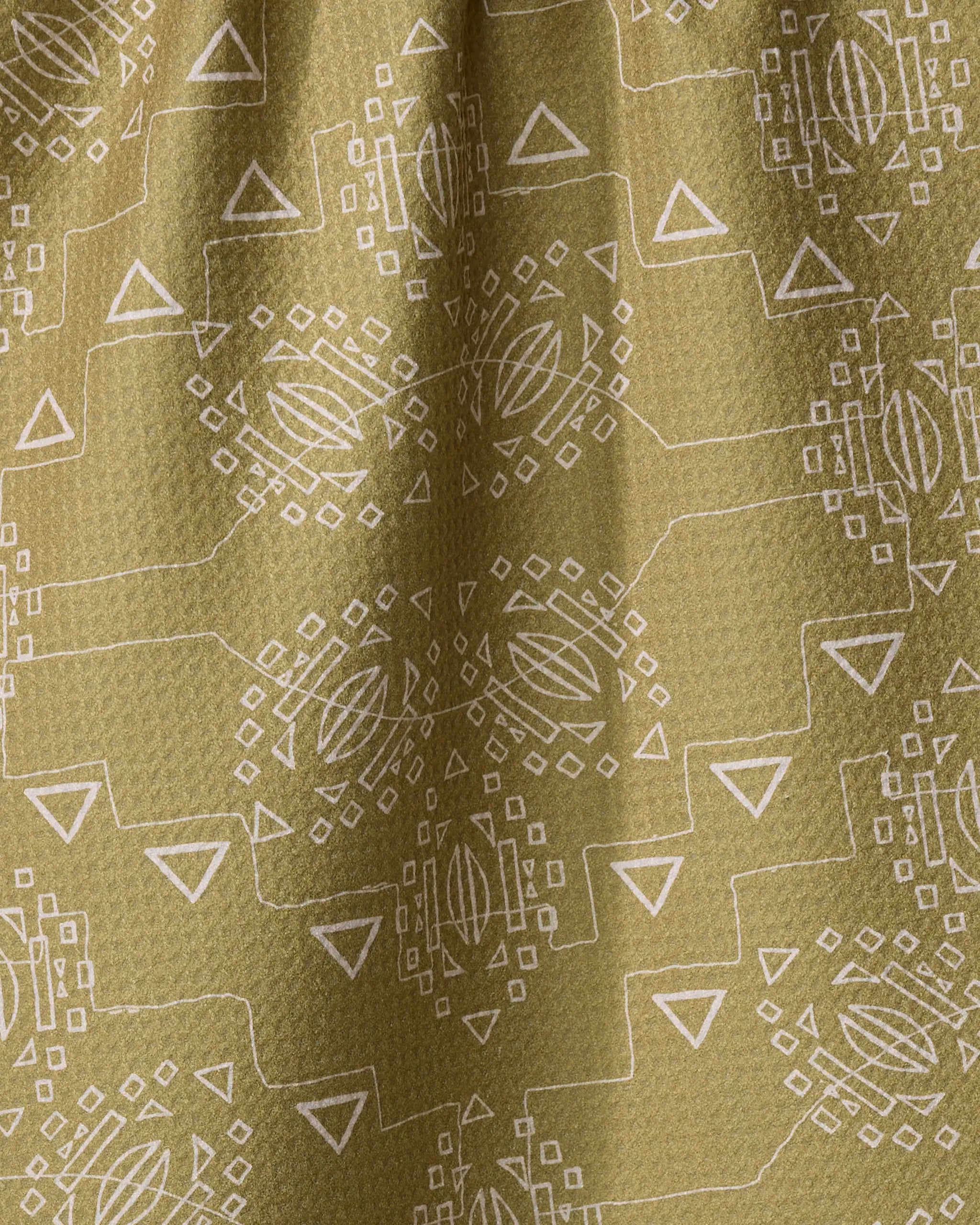 A close-up of Mountain Bloom by Ash Cascade highlights textured olive-green fabric with a white geometric pattern, crafted from quick-drying recycled materials.