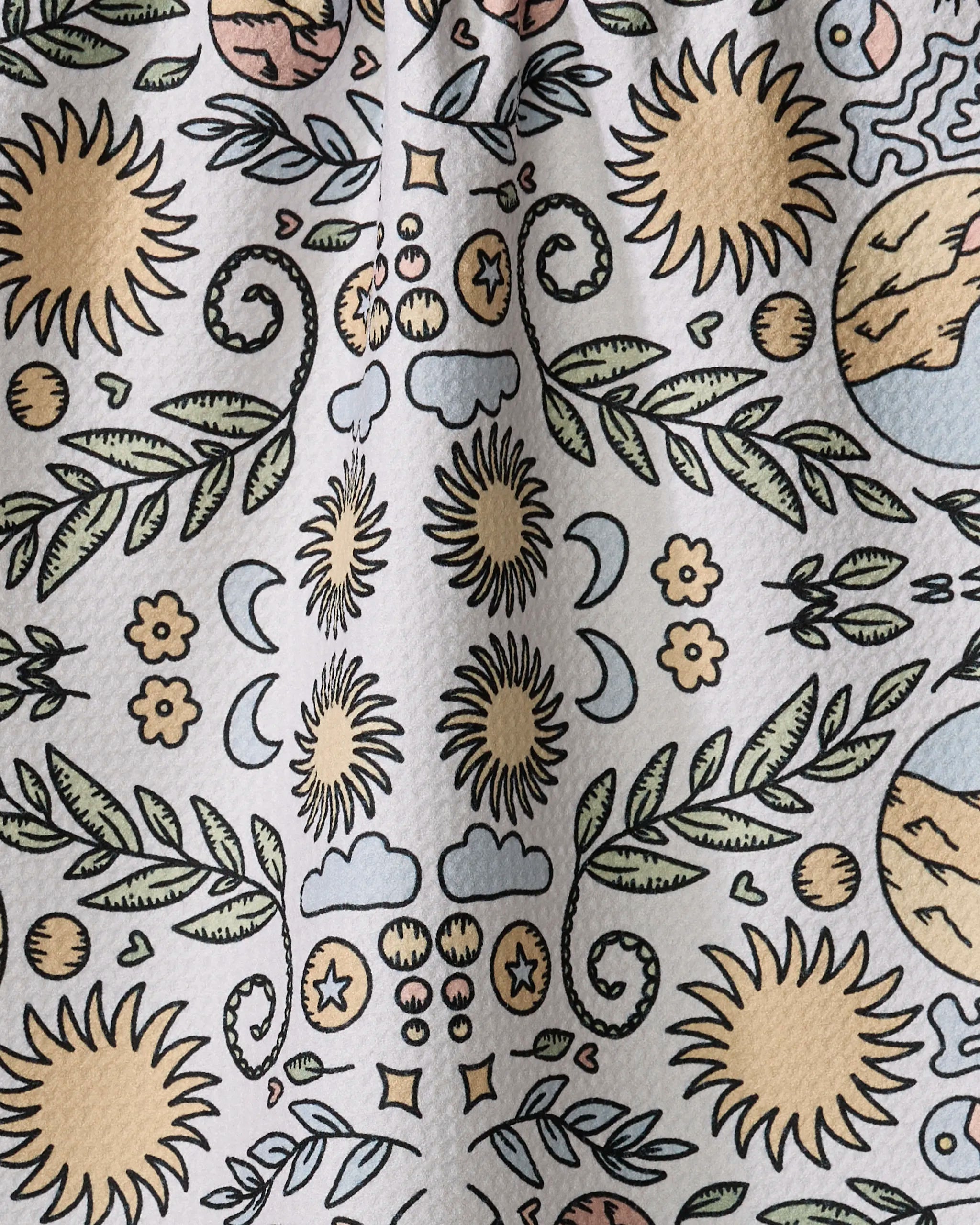 The Mountain Mosaic tea towel by Graphics and Grain is made from recycled materials and features hand-drawn sunflowers, moons, stars, vines, and abstract circles in muted yellow, green, and brown on a light background.