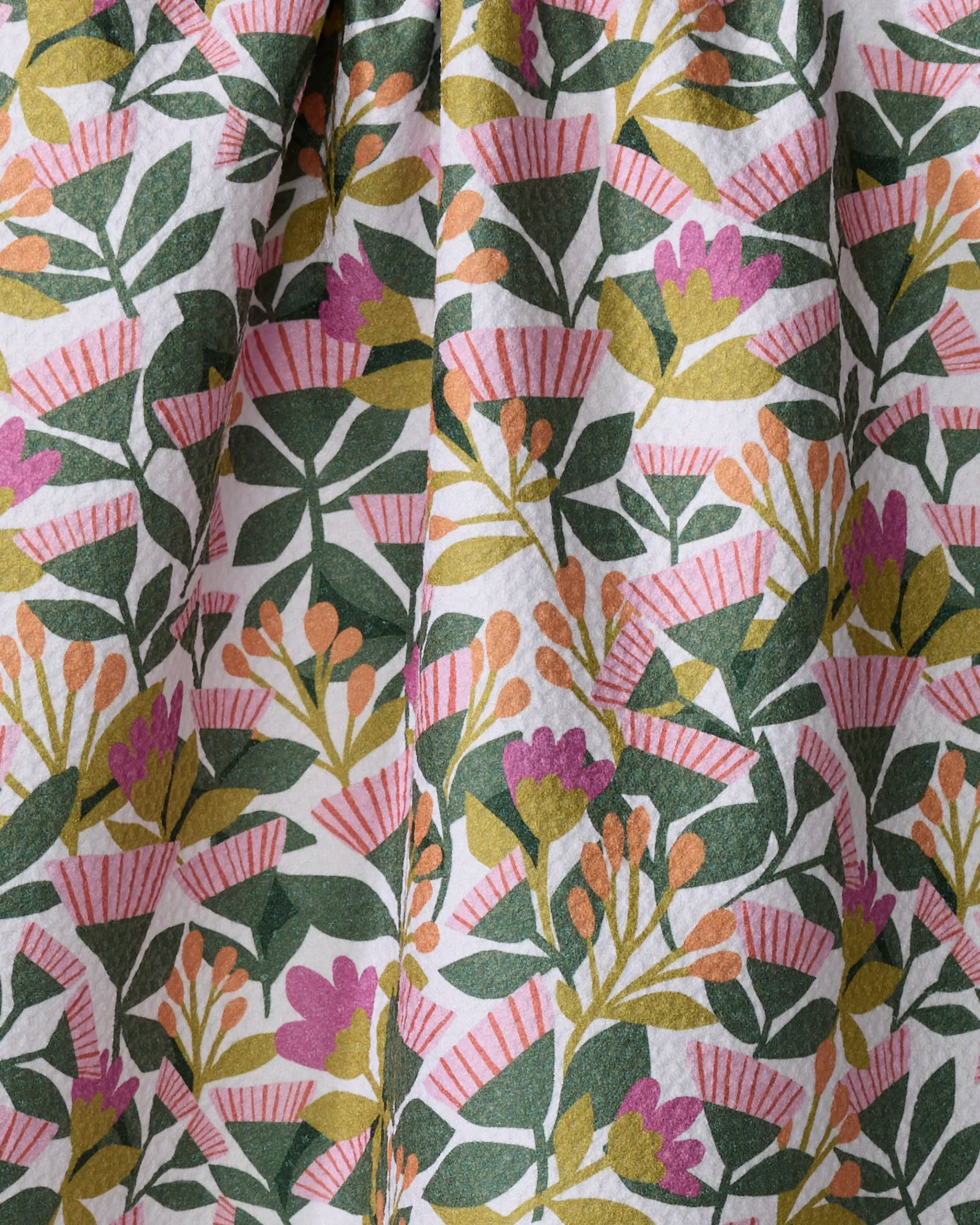 The Moxie Mauve tea towel by Lisa Nelson features a botanical pattern of green leaves, vibrant flowers, and berries on white. Made from recycled materials, it’s ultra-absorbent, colorful, and drapes softly with gentle folds.
