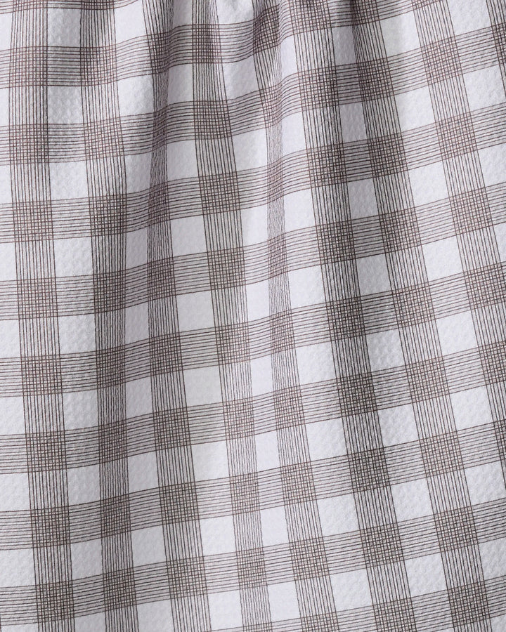 A close-up of The Buy Guide’s Multi Gingham - Chocolate recycled kitchen towel, featuring a white base with a brown plaid grid and slightly textured, gathered fabric near the top.