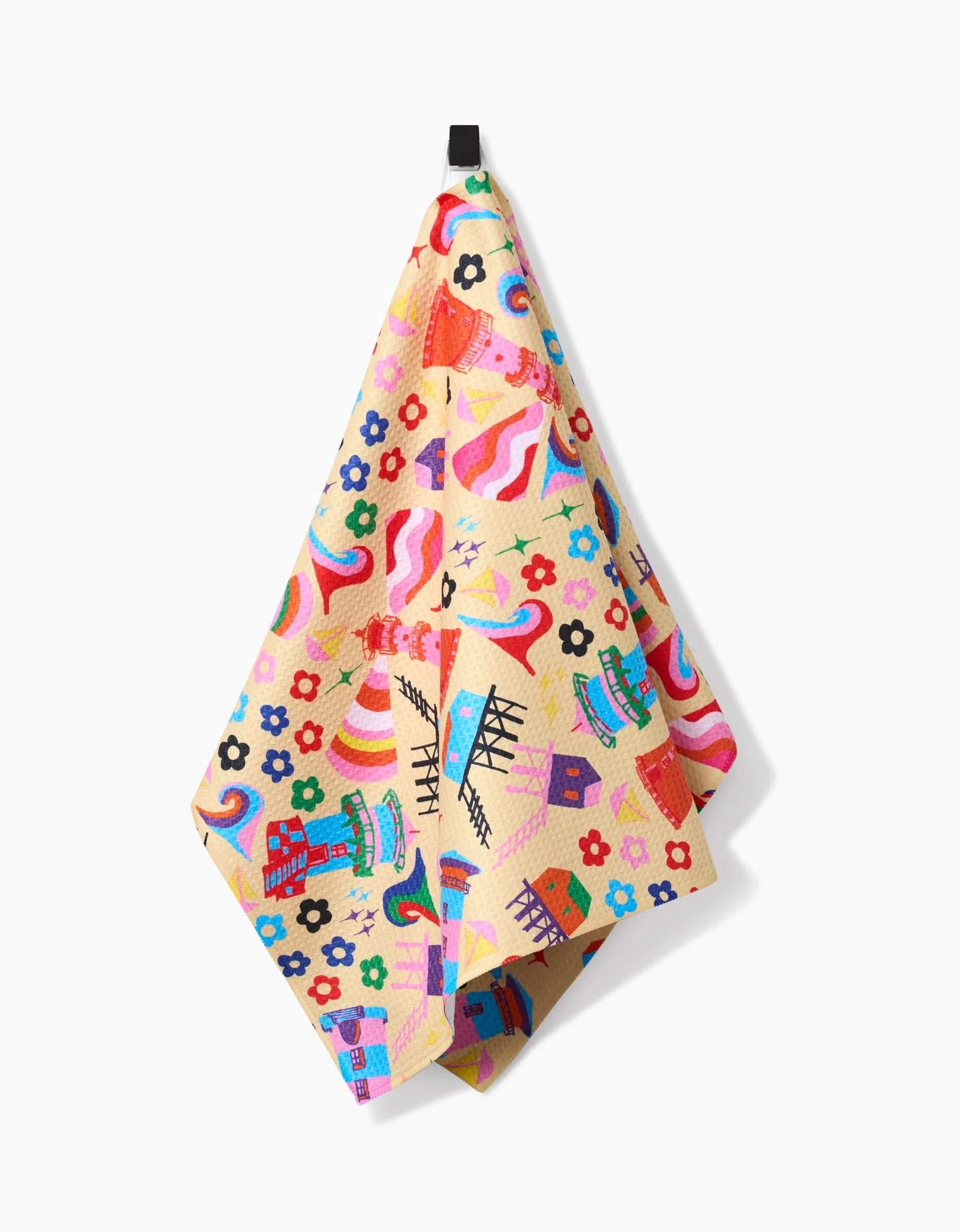 The My Place tea towel by Ania Zwara Art features whimsical houses, ferris wheels, rainbows, and flowers. Made from recycled materials for an eco-friendly touch, it hangs on a black hook against a white background.
