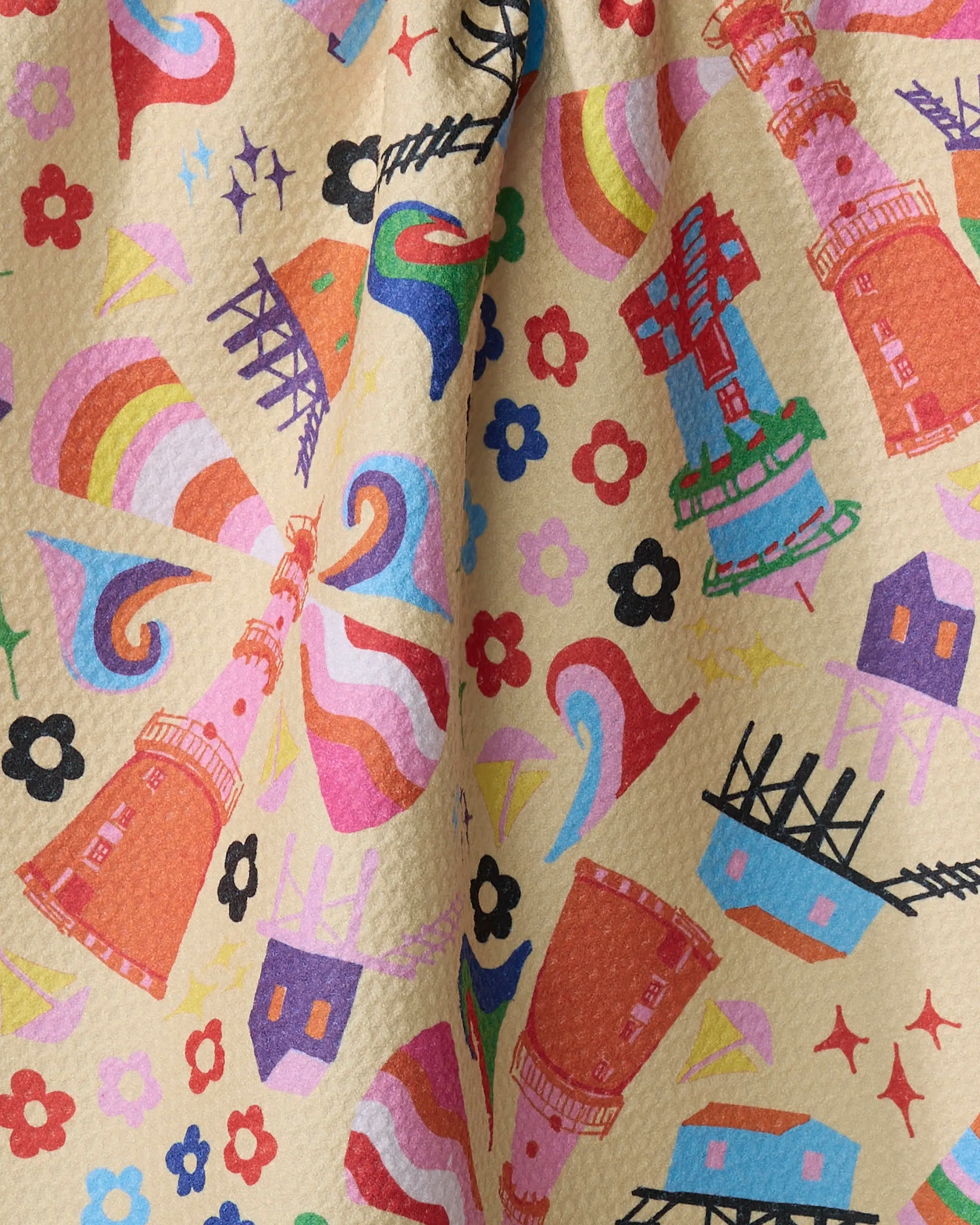 The My Place dish towel by Ania Zwara Art features a colorful pattern of red towers, windmills, rainbows, sailboats, houses, flowers, and waves on absorbent light beige fabric.