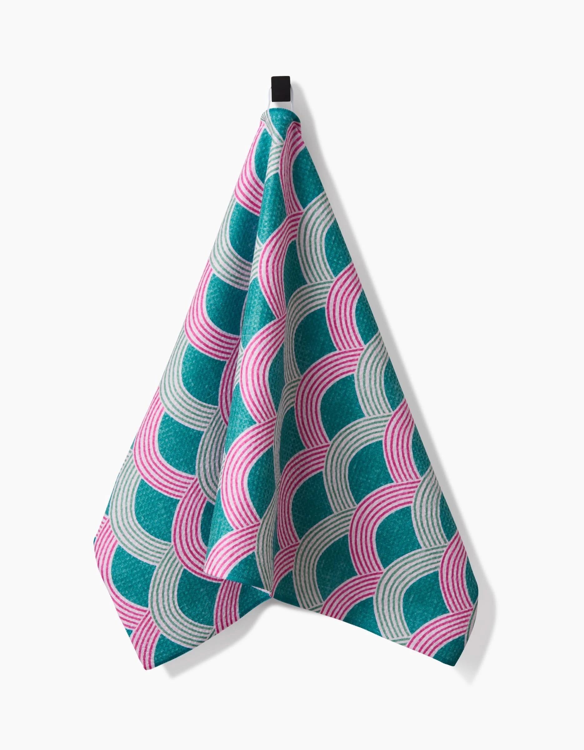 The Nalin tea towel by Amy MacCready features a geometric pattern of overlapping teal, pink, and light gray semi-circles on white Geoweave fabric, with a black hanging loop for easy display.