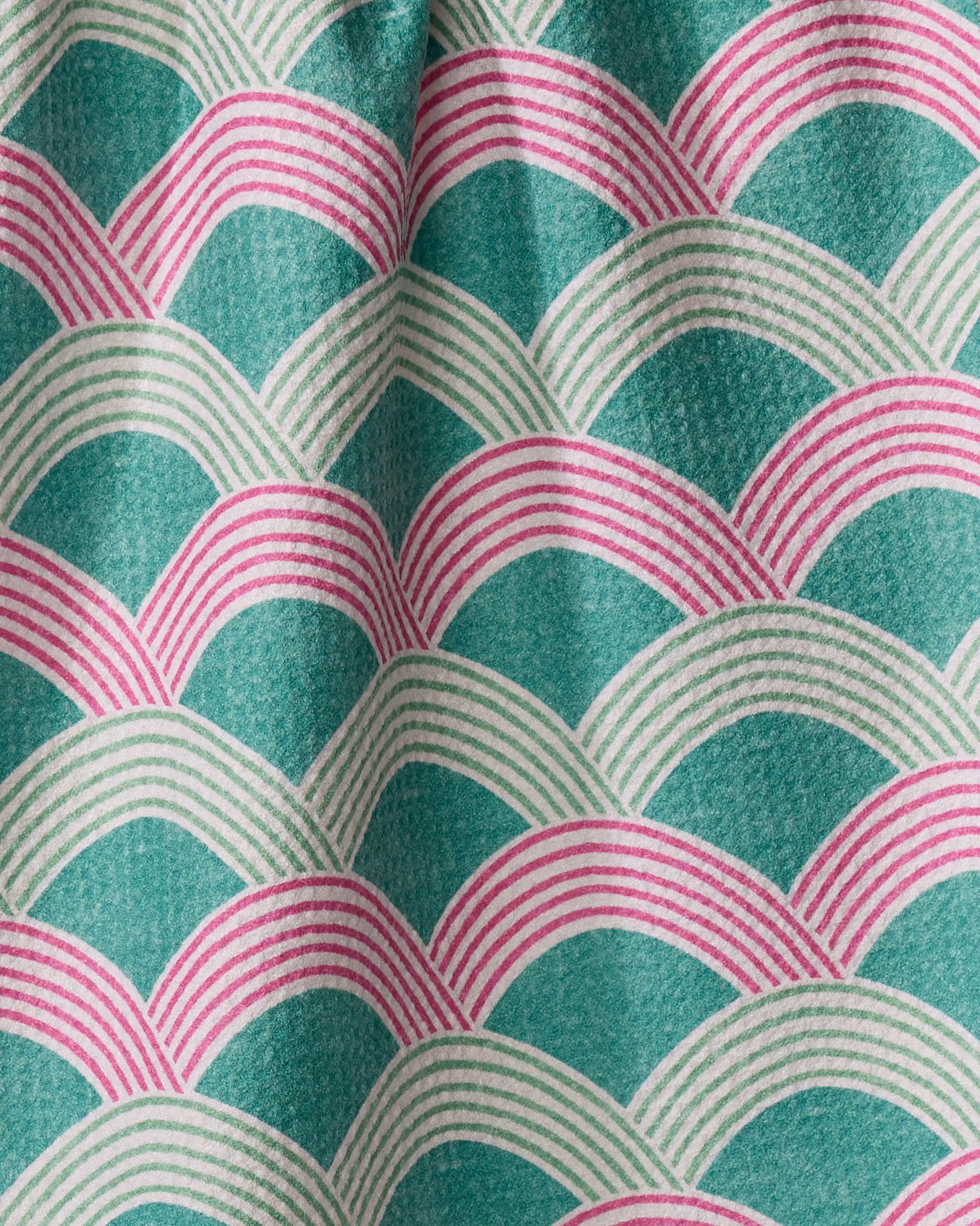 Close-up of the Nalin tea towel by Amy MacCready, made from recycled materials. It features a scallop pattern in teal, white, and pink on ultra-absorbent, soft fabric with gentle folds for a layered wavelike effect.