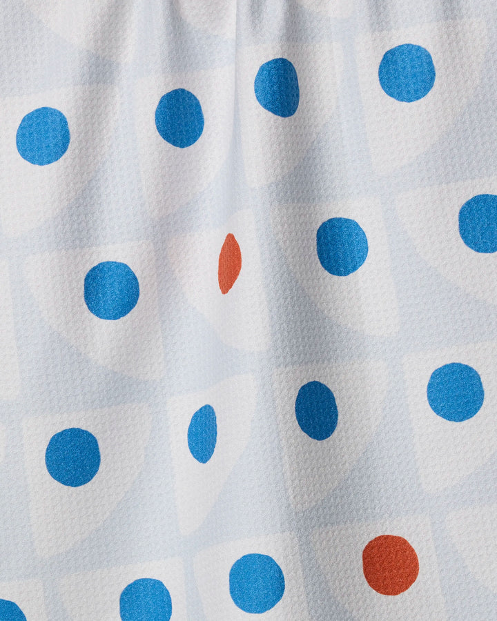 Close-up of Geometry's Nautical Eye recycled kitchen towel, featuring blue and red dots on a white grid. This ultra-absorbent towel boasts a slightly textured, wrinkled surface and is set against a light background.