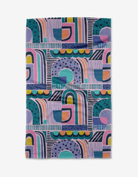 The New Dawn towel by Masha Volnova is a rectangular quick-drying towel with a bold, modern geometric pattern in purple, teal, blue, orange, pink, and yellow featuring arches, circles, dots, and lines.